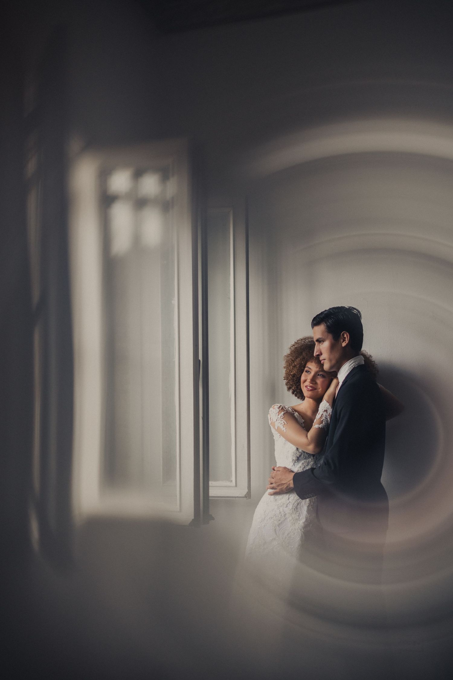 Intimate wedding moment captured through a dark vignette with dramatic lighting and shadows.
