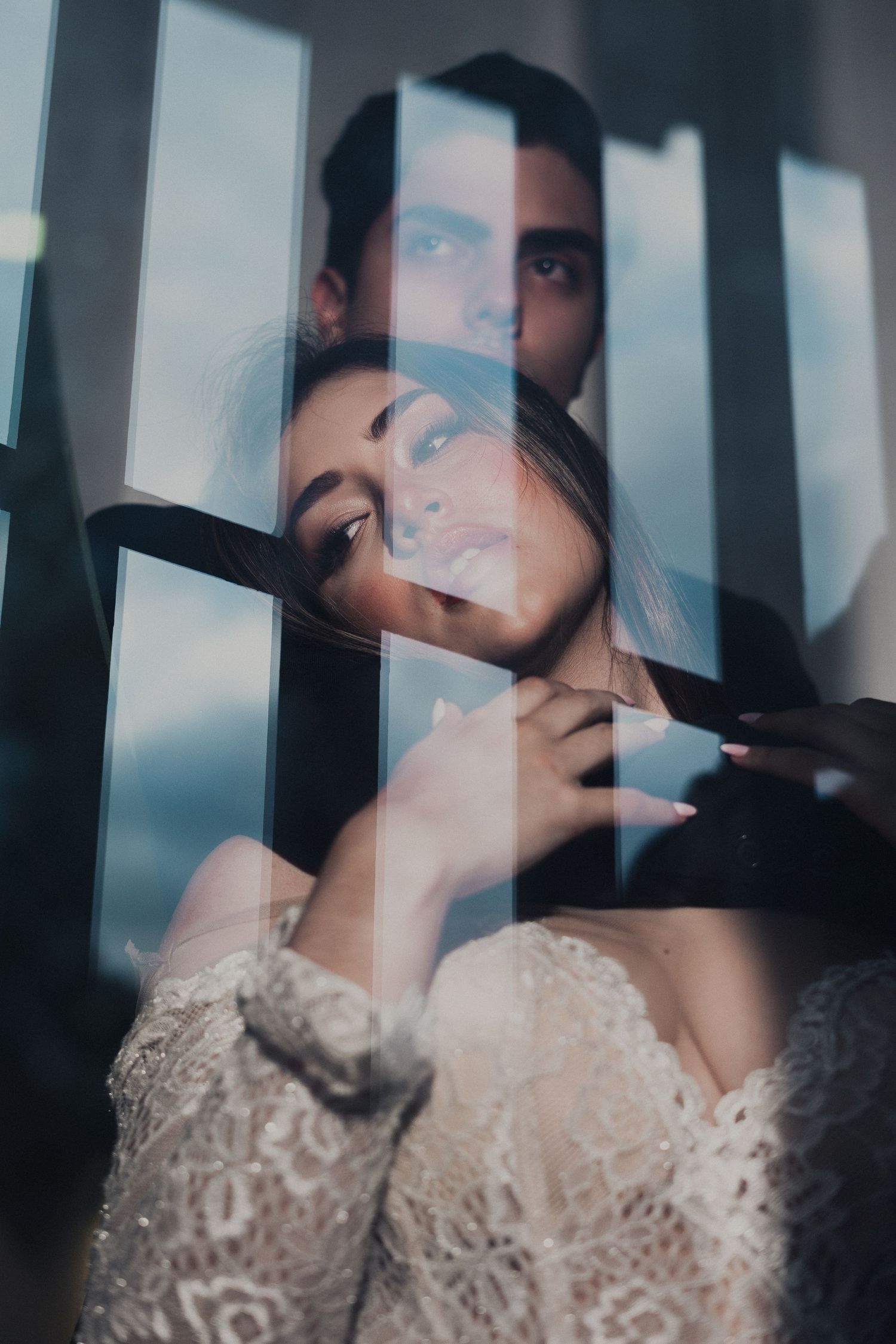 Artistic portrait through window blinds creating dramatic shadows and light patterns.