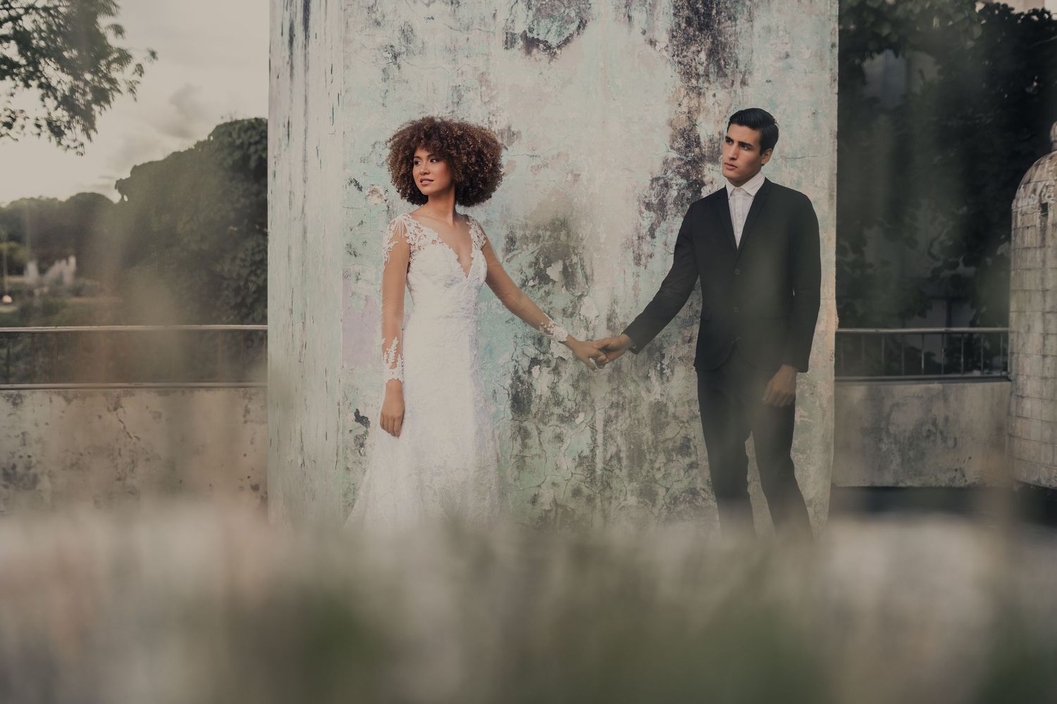 Romantic wedding photo session against weathered walls and garden scenery.