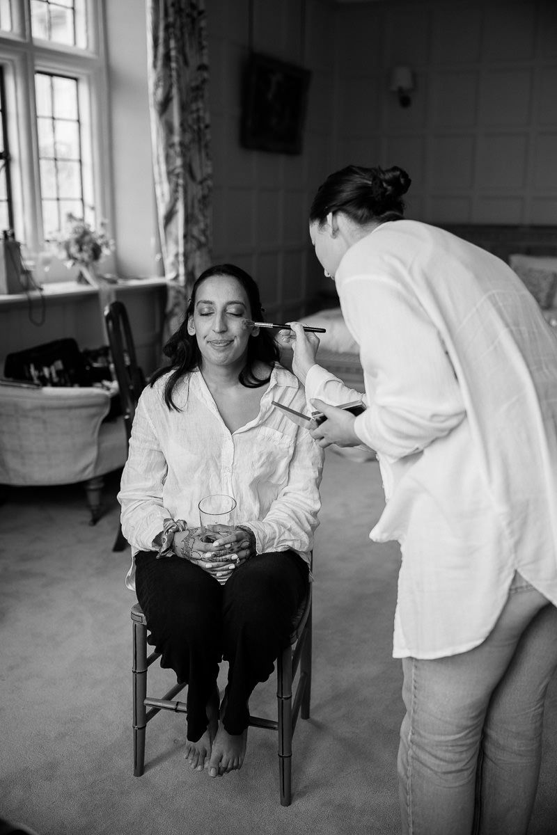 Black and white photo series showing someone seated in a chair while another person in white approaches at mapledurham house wedding venue.