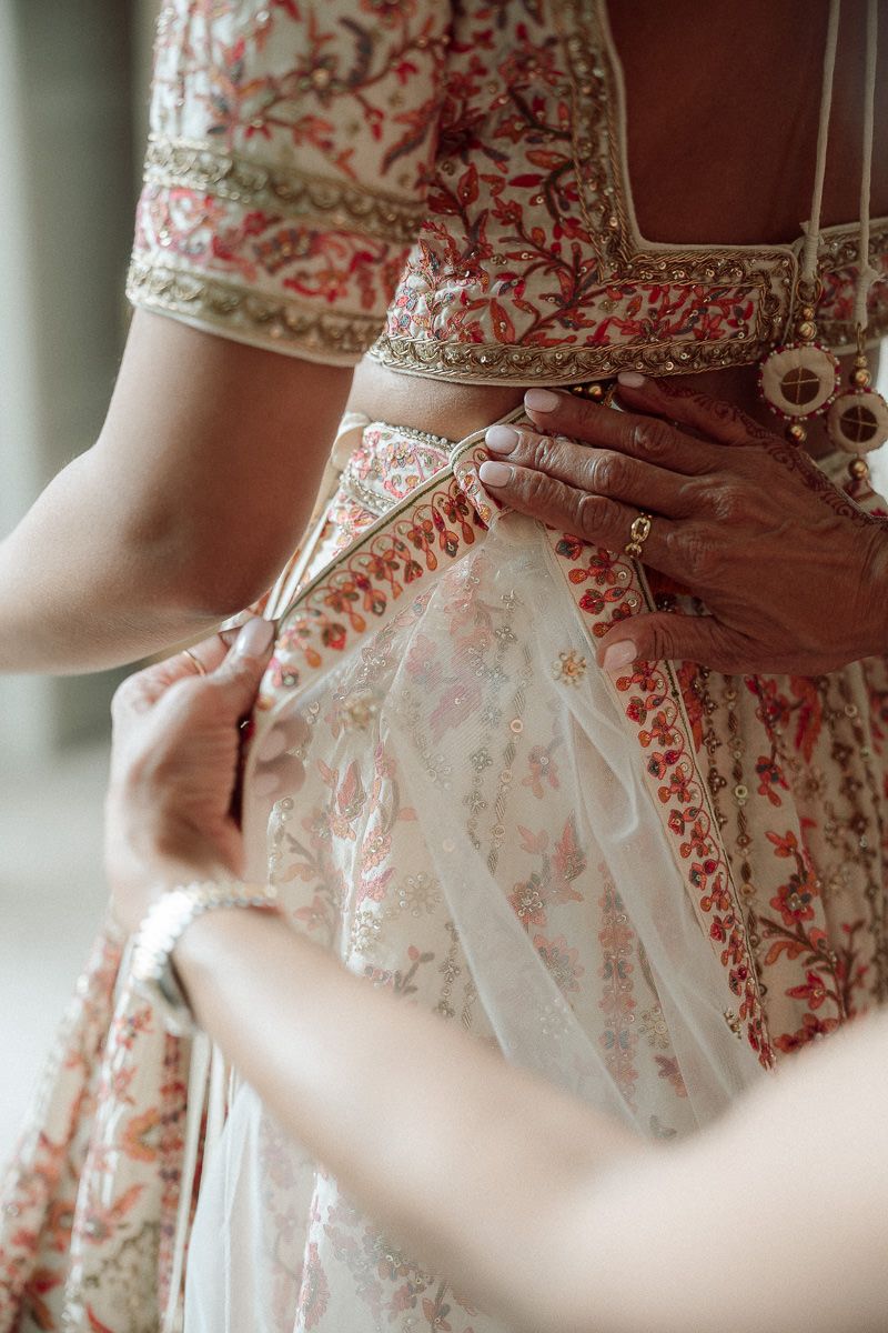 Close-up details of a delicate white and red floral patterned dress with intricate lace embellishments.