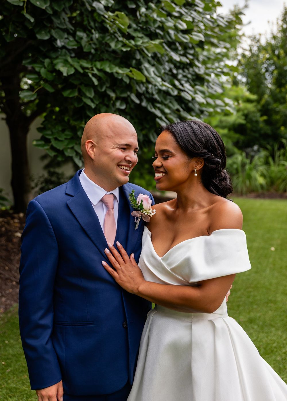 Joyful wedding couple sharing a candid moment together in an outdoor garden setting.