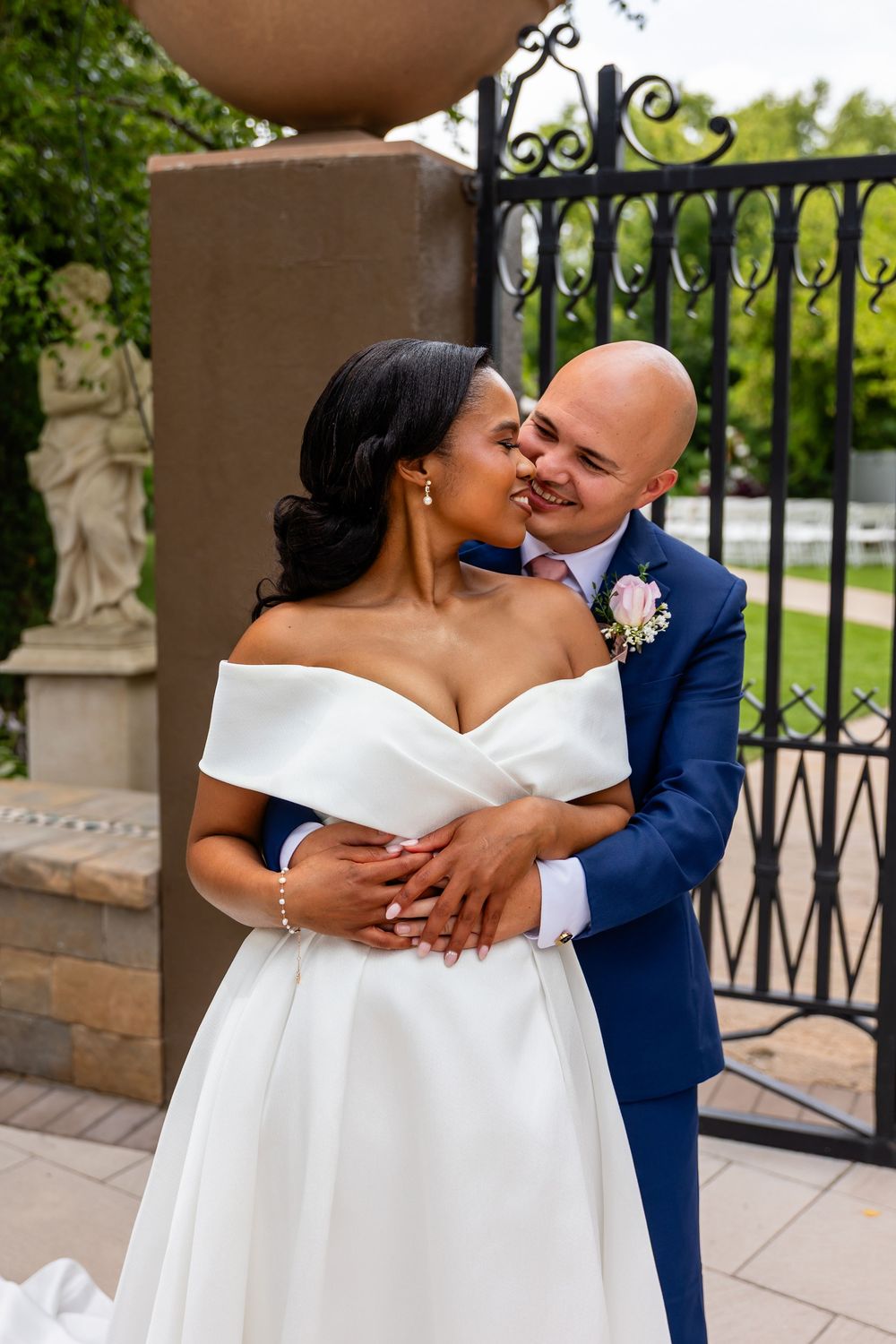 Intimate wedding portrait against an ornate iron railing with stone pillars at Villa Aletta in Omaha, NE.