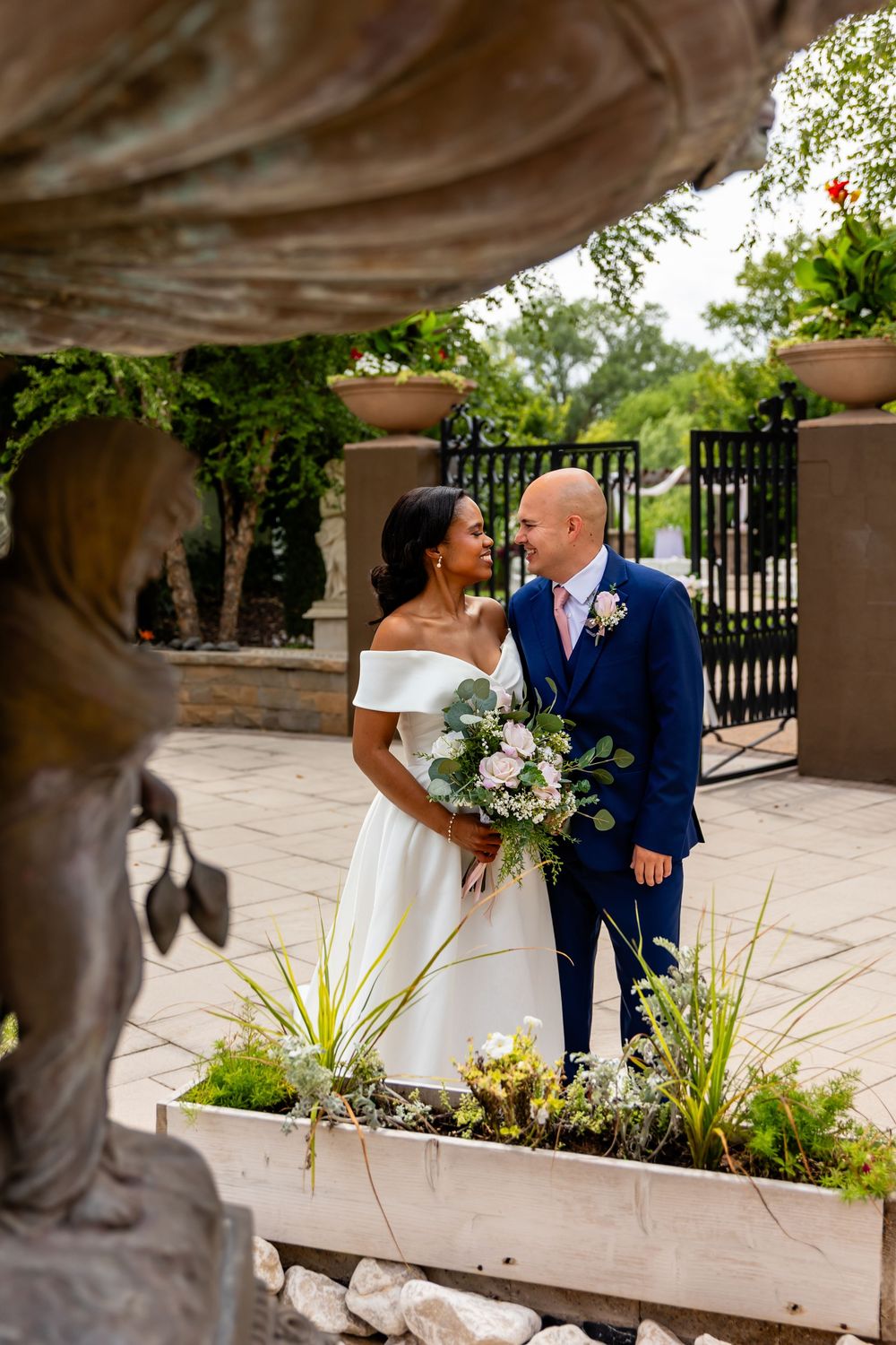 Romantic wedding portrait by stone planters and iron railings in an outdoor garden setting at Villa Aletta in Omaha, NE.