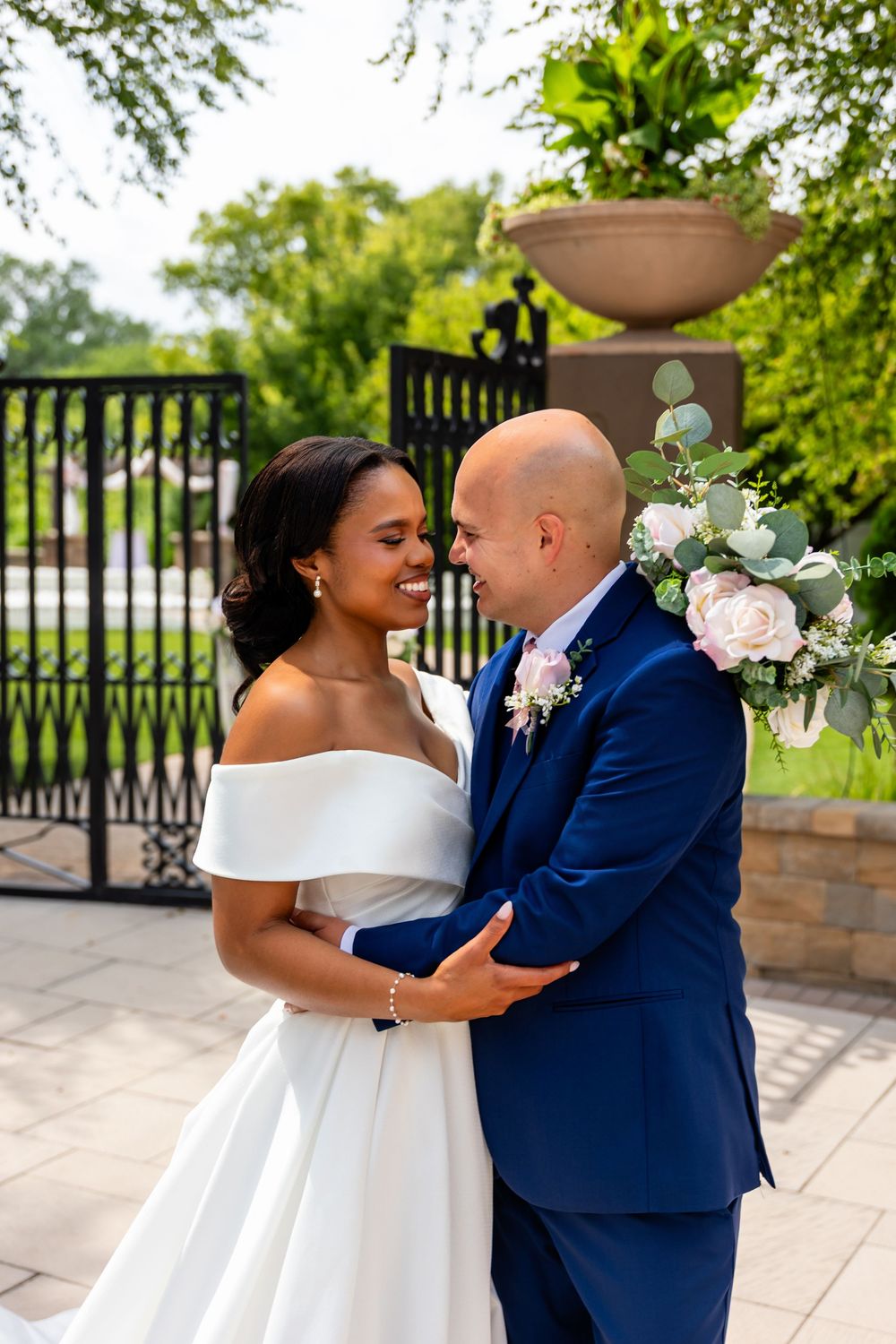Candid wedding moment captured against lush garden greenery and stone architecture at Villa Aletta in Omaha, NE.