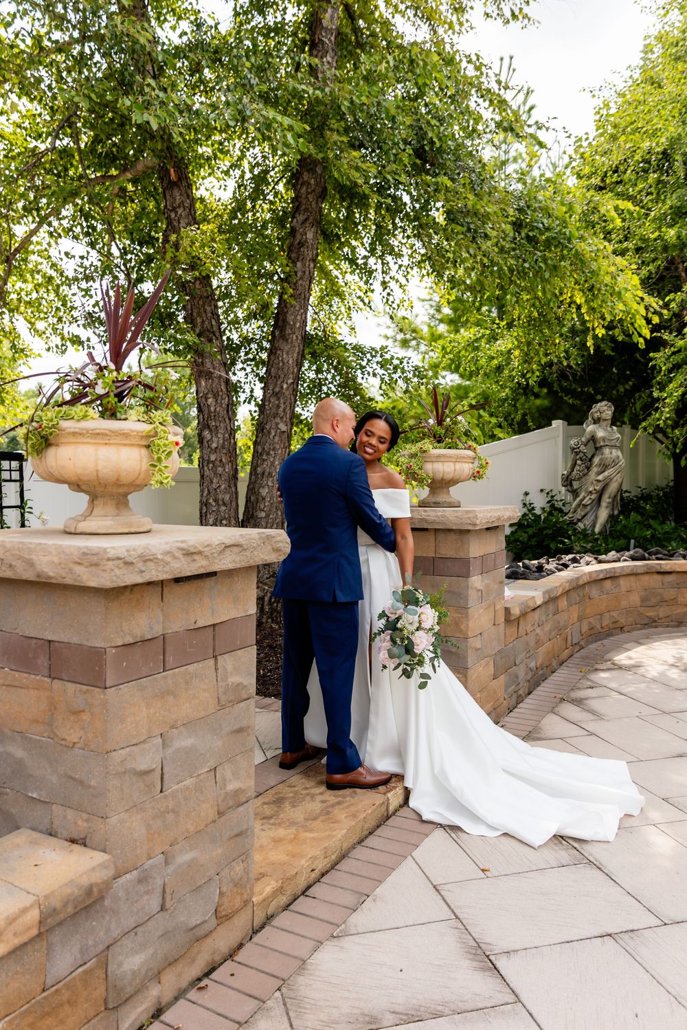 Wedding couple photographed along a stone wall pathway in a garden setting at Villa Aletta in Omaha, NE.