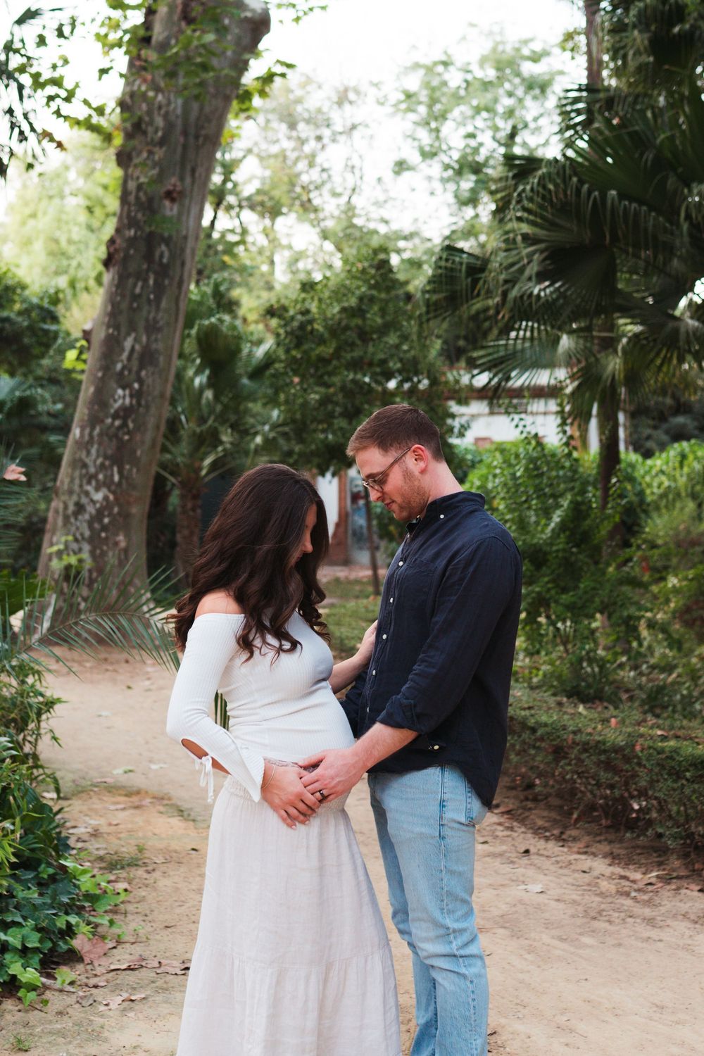 A couple shares an intimate moment on a garden path surrounded by lush greenery.
