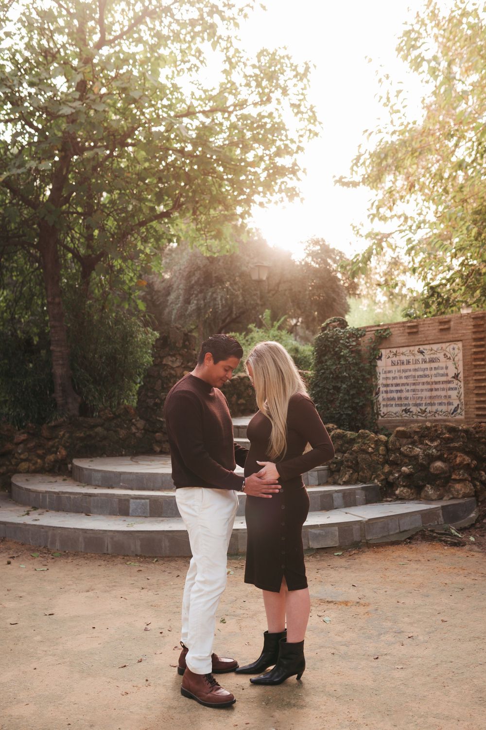 Couple sharing tender moment on garden path during sunset photoshoot.