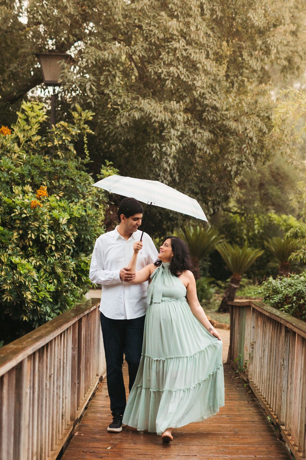 Couple sharing romantic moments on a wooden boardwalk with white umbrella and mint green dress.
