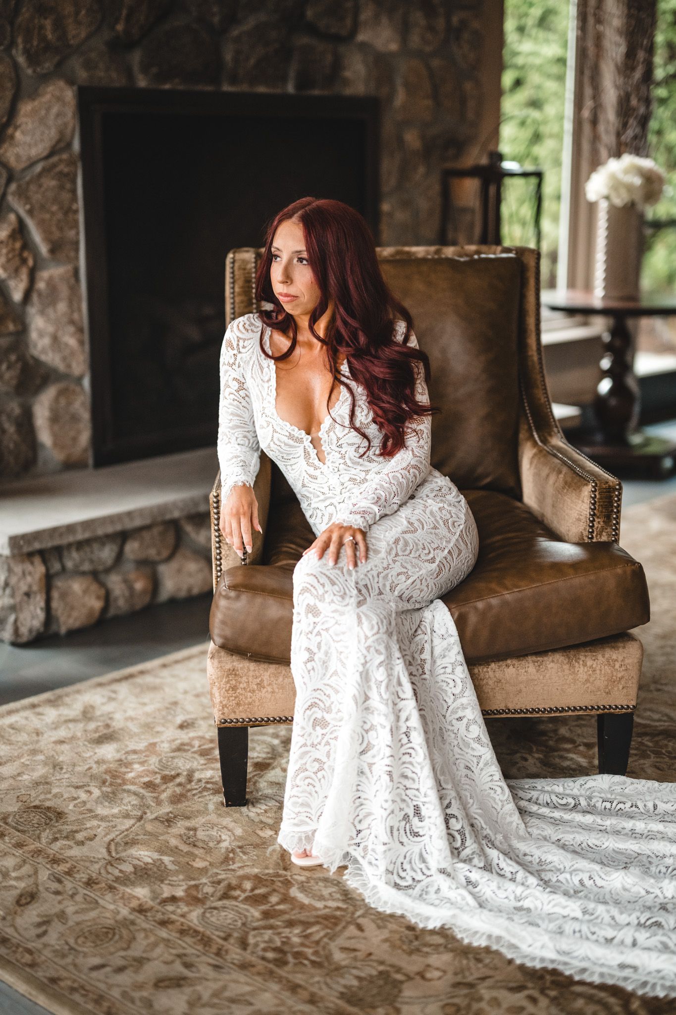 Elegant bridal portraits featuring a lace wedding dress against stone walls and leather furniture.