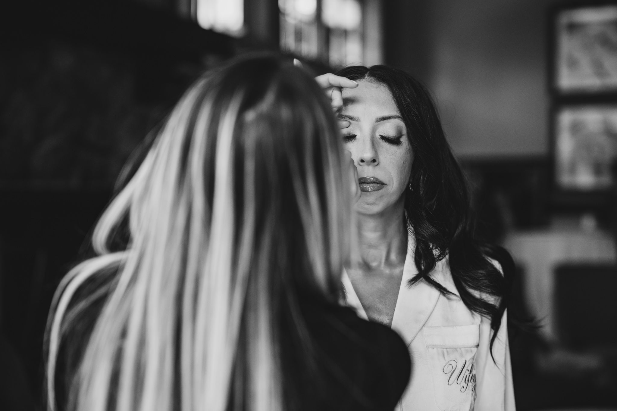 Black and white getting ready moments captured in moody indoor lighting.
