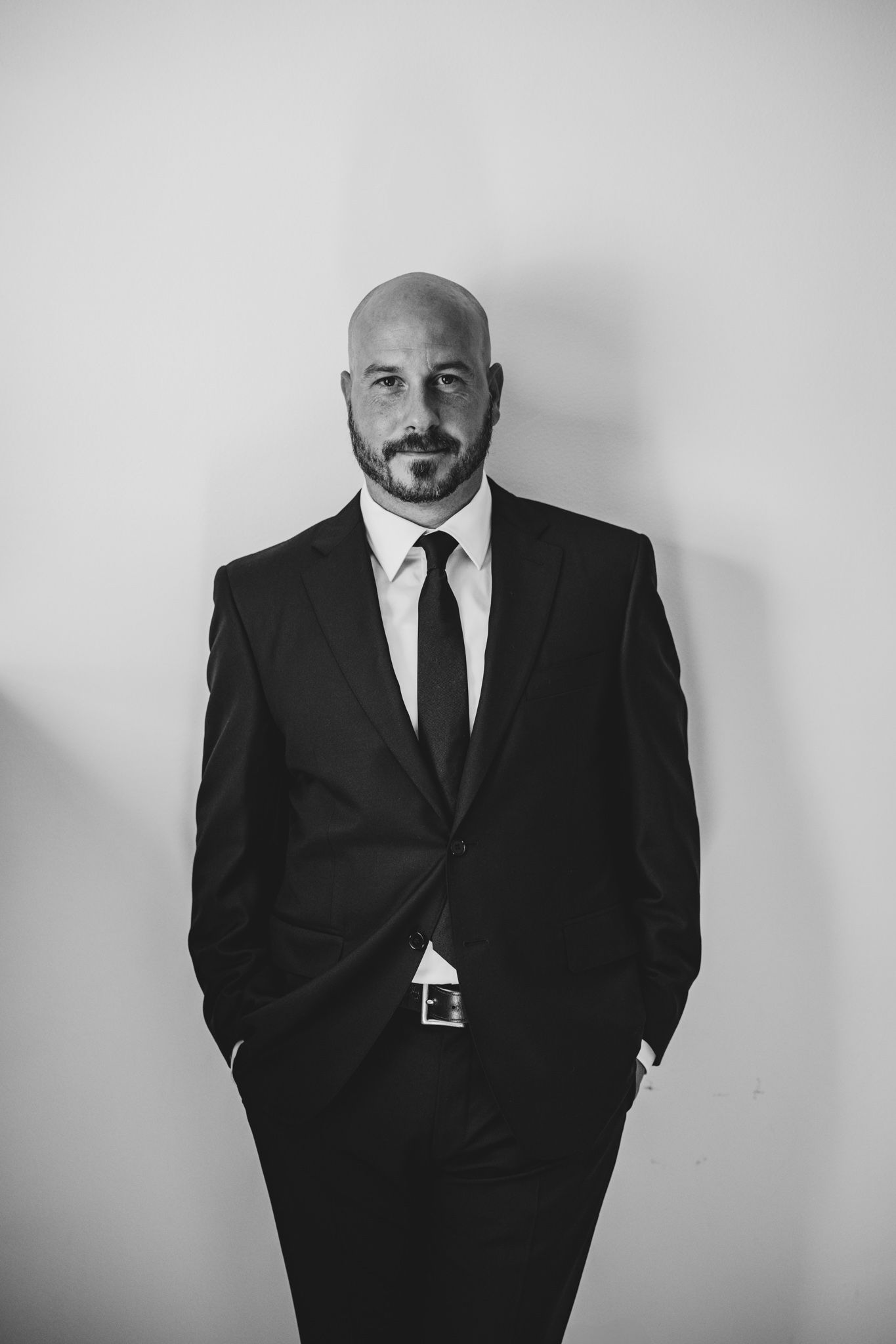 Professional portraits in black and white showing formal attire against white wall.