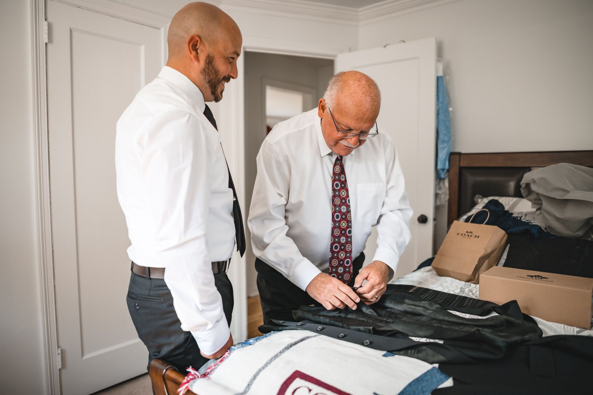 Two people in formal wear adjusting clothing and accessories before an event.