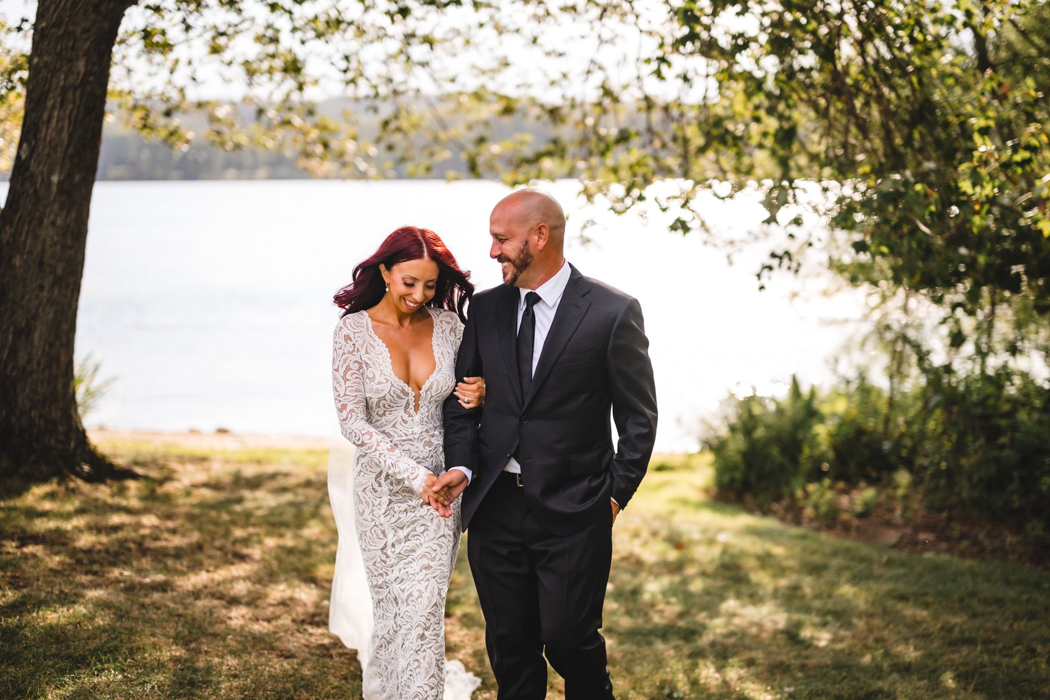 Elegant wedding portrait by lakeside with autumn trees in background.