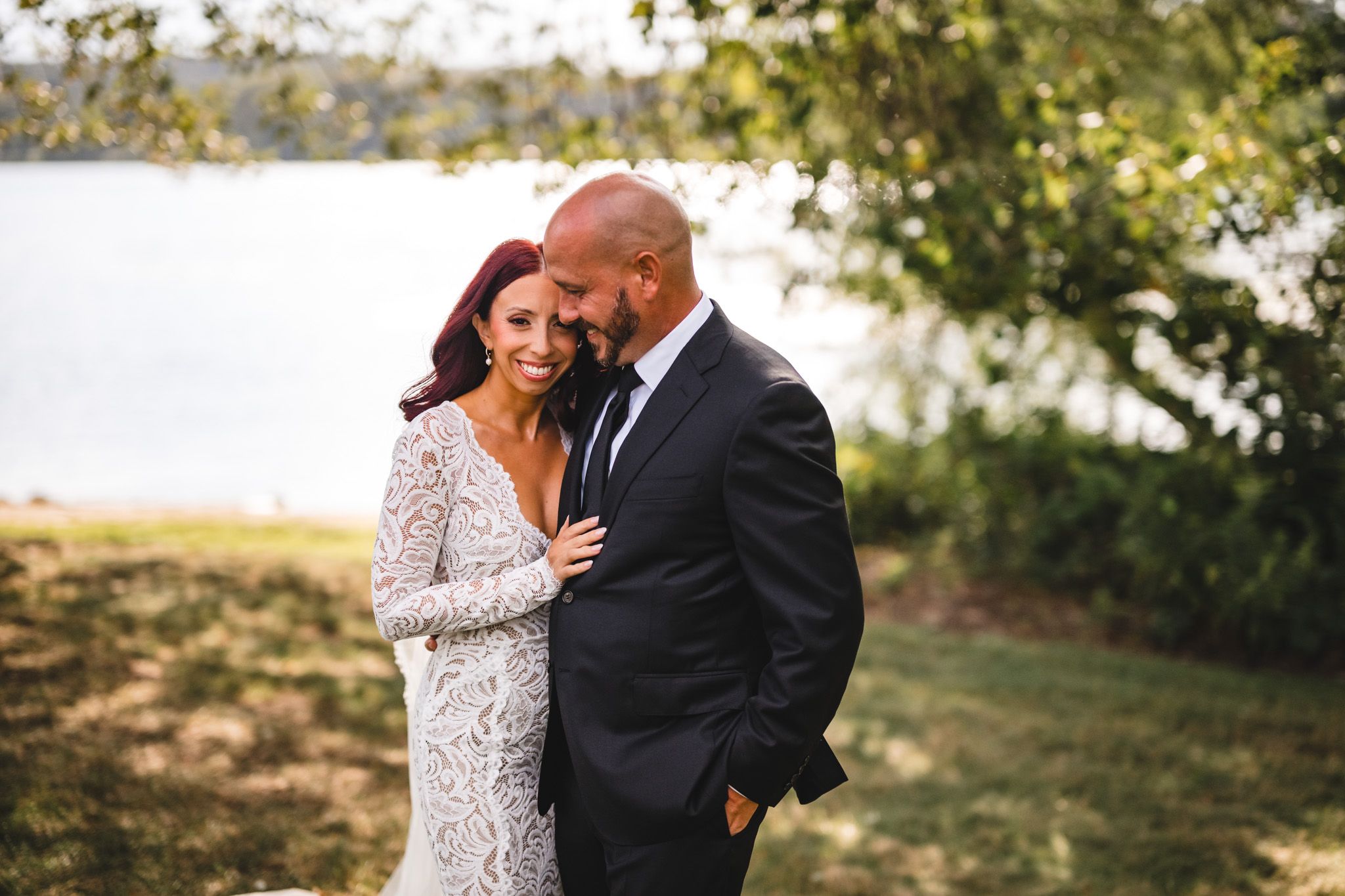 Romantic waterfront wedding portrait with natural lighting and fall foliage.