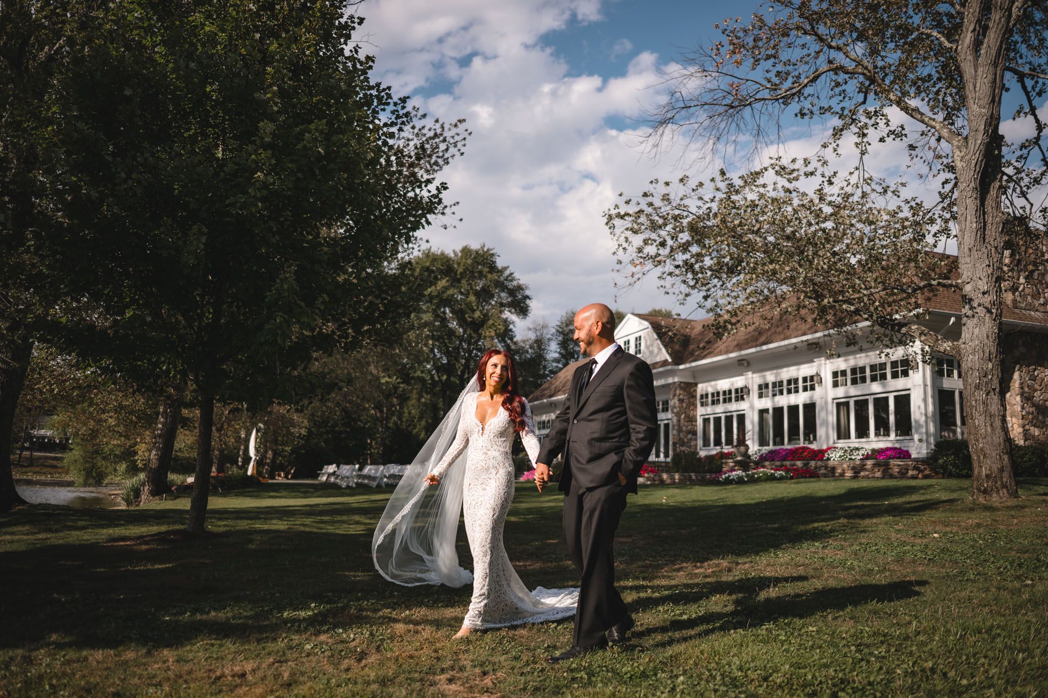 Wedding portraits taken on a scenic lawn with a white building in the background.