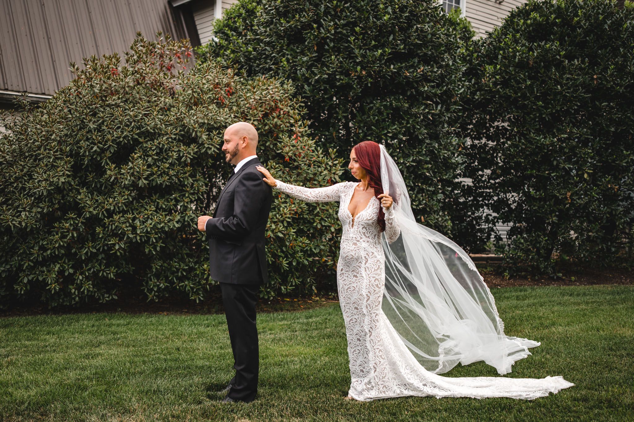 Wedding couple poses on winding garden path with flowing white dress.