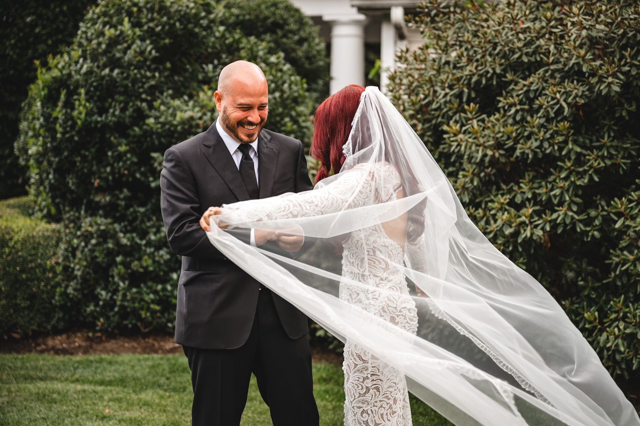A wedding moment captured outdoors as a veil flows dramatically in the breeze.