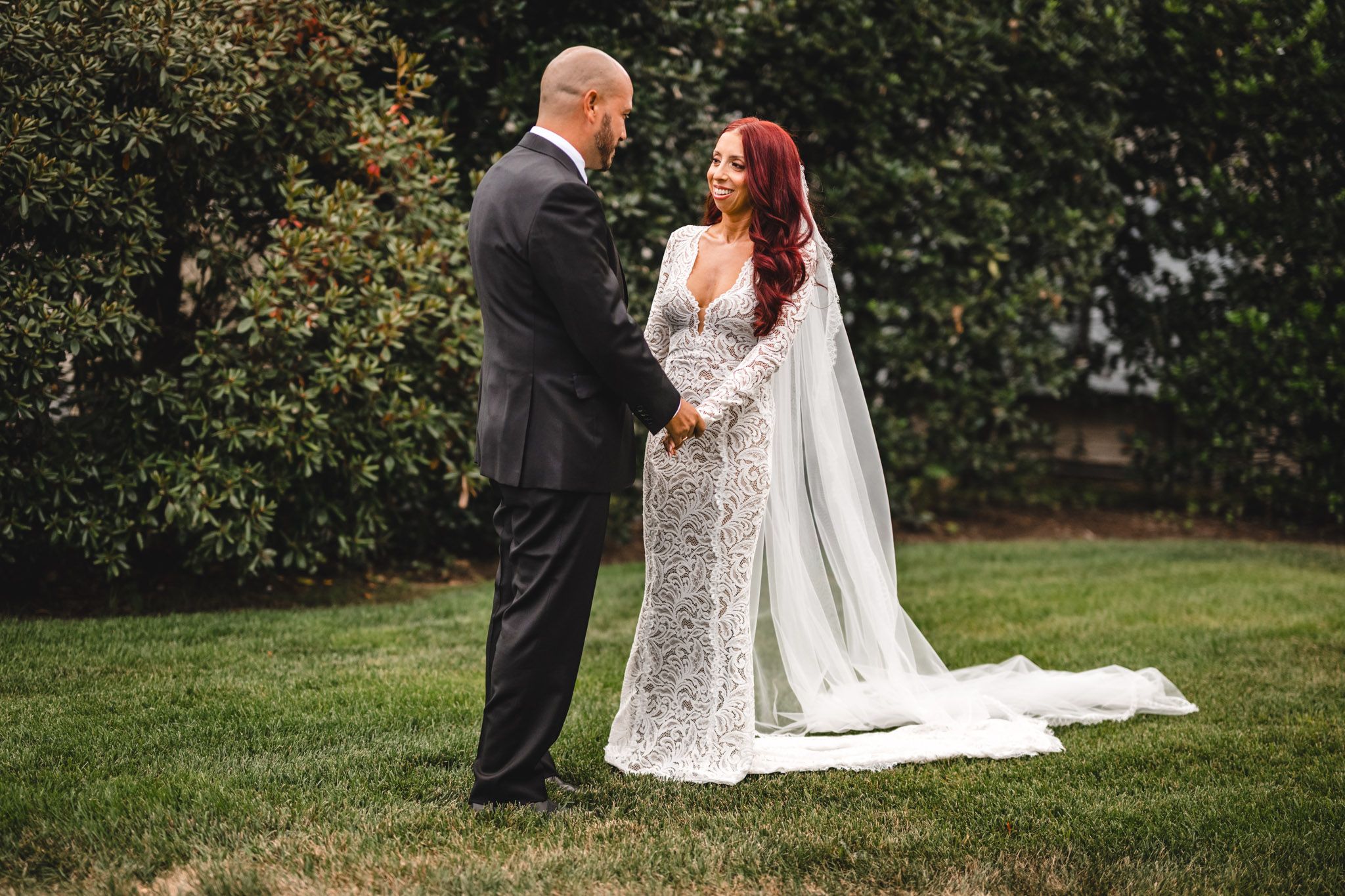 A romantic outdoor wedding scene with a long flowing veil and lace dress.