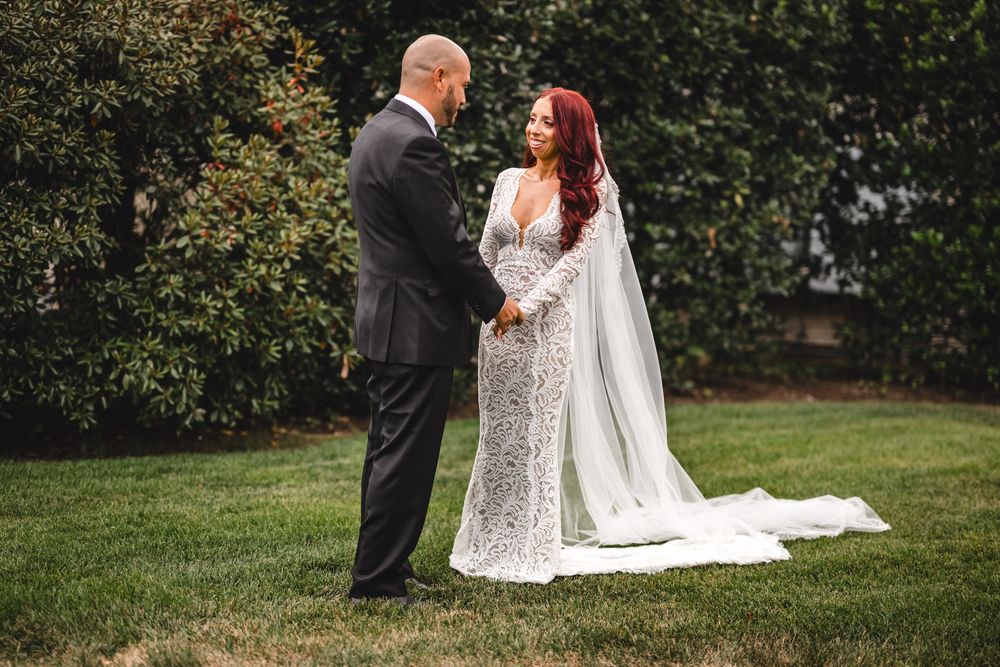 A romantic outdoor wedding scene with a long flowing veil and lace dress.
