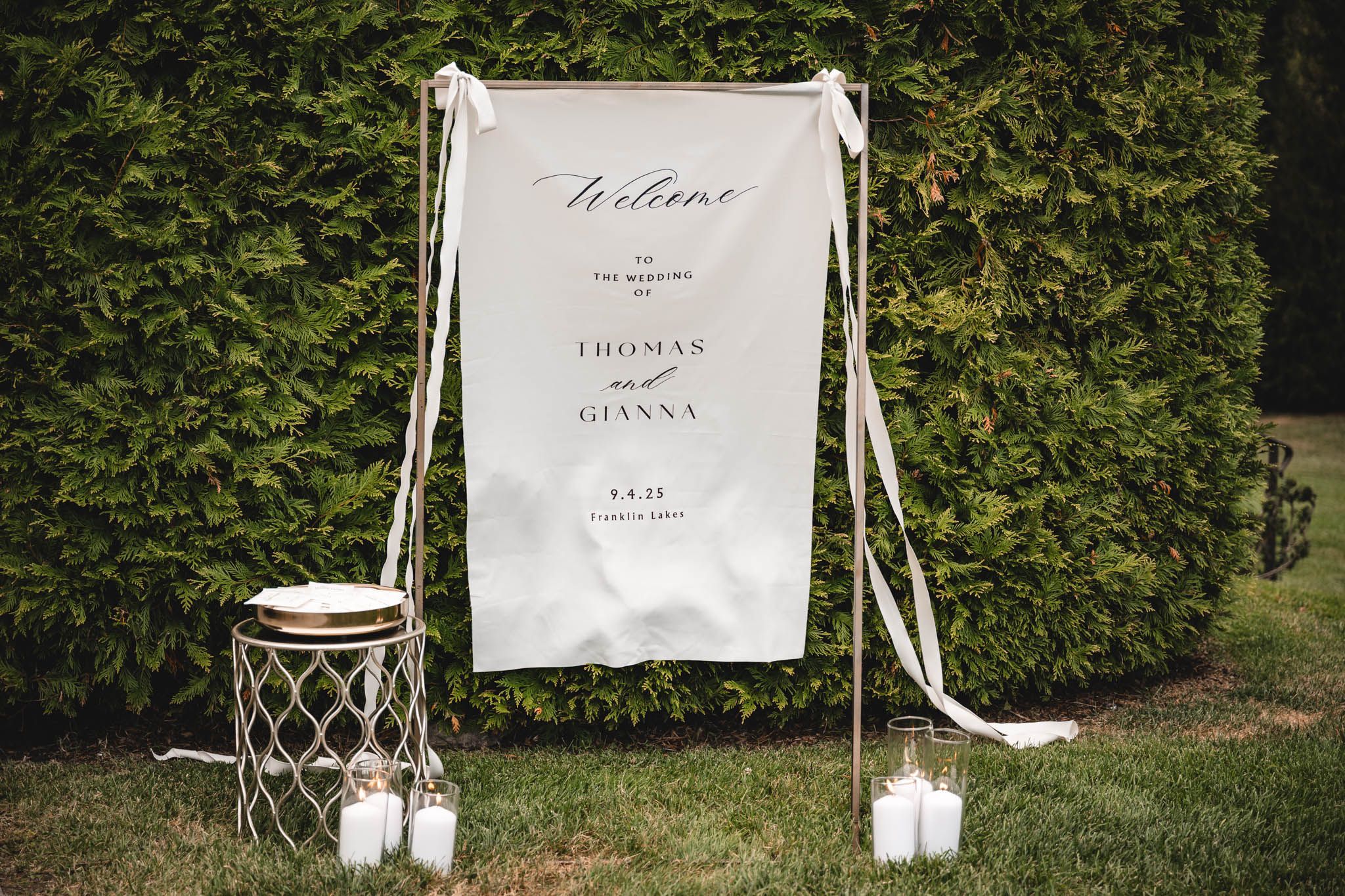 Wedding welcome signs and decorative elements displayed on white easels with greenery.