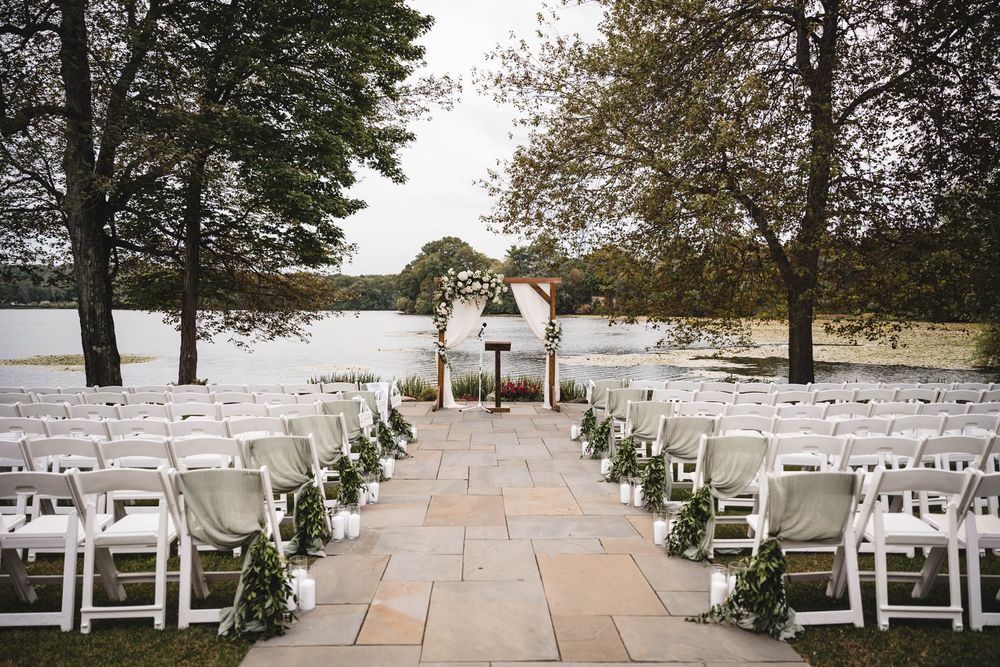 Outdoor wedding ceremony setup with white chairs arranged on a stone patio.