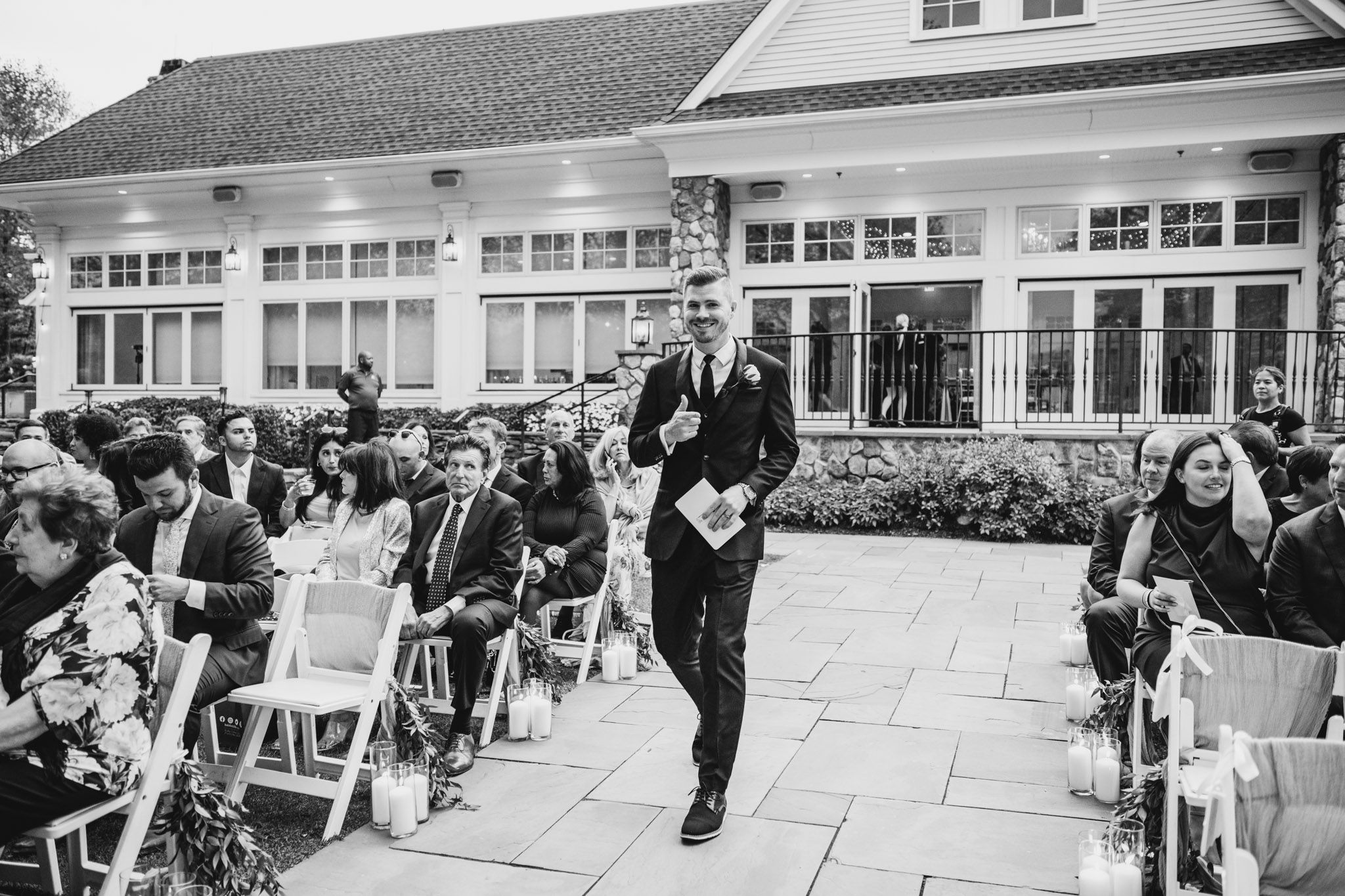 Wedding guests gather on a stone patio during an outdoor reception.