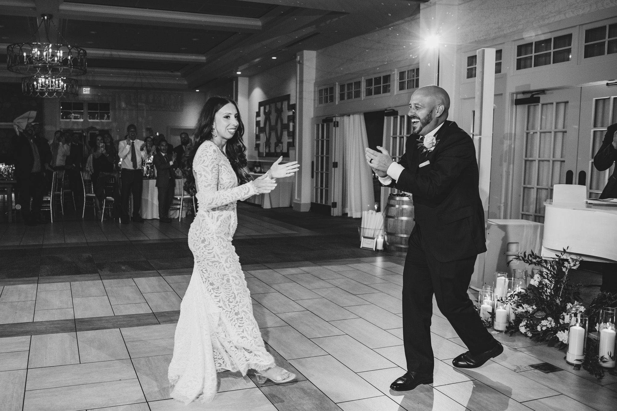 Black and white photo of dancing celebration on elegant tiled floor.