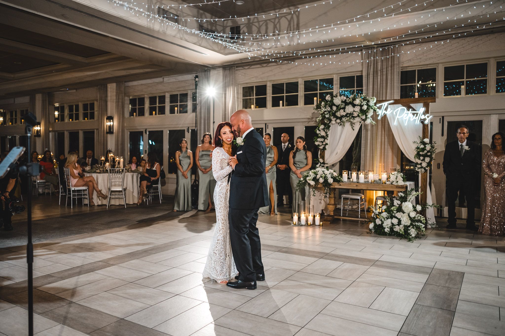 A couple shares their first dance at an elegant wedding reception with guests watching from the sidelines.