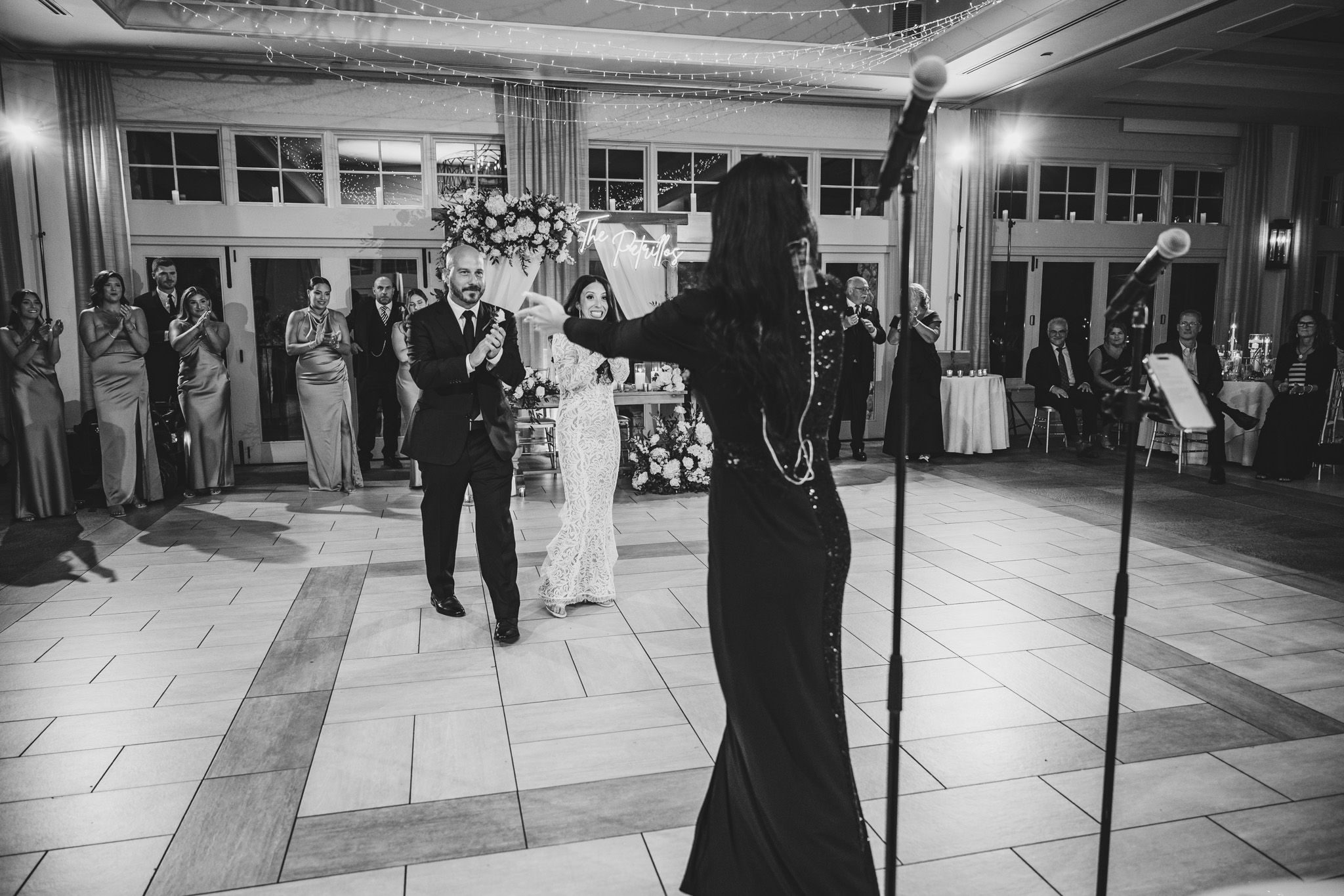 Black and white photo of a wedding dance with guests watching in an elegant ballroom setting.