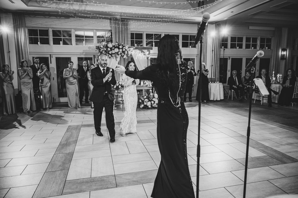 Black and white photo of a wedding dance with guests watching in an elegant ballroom setting.