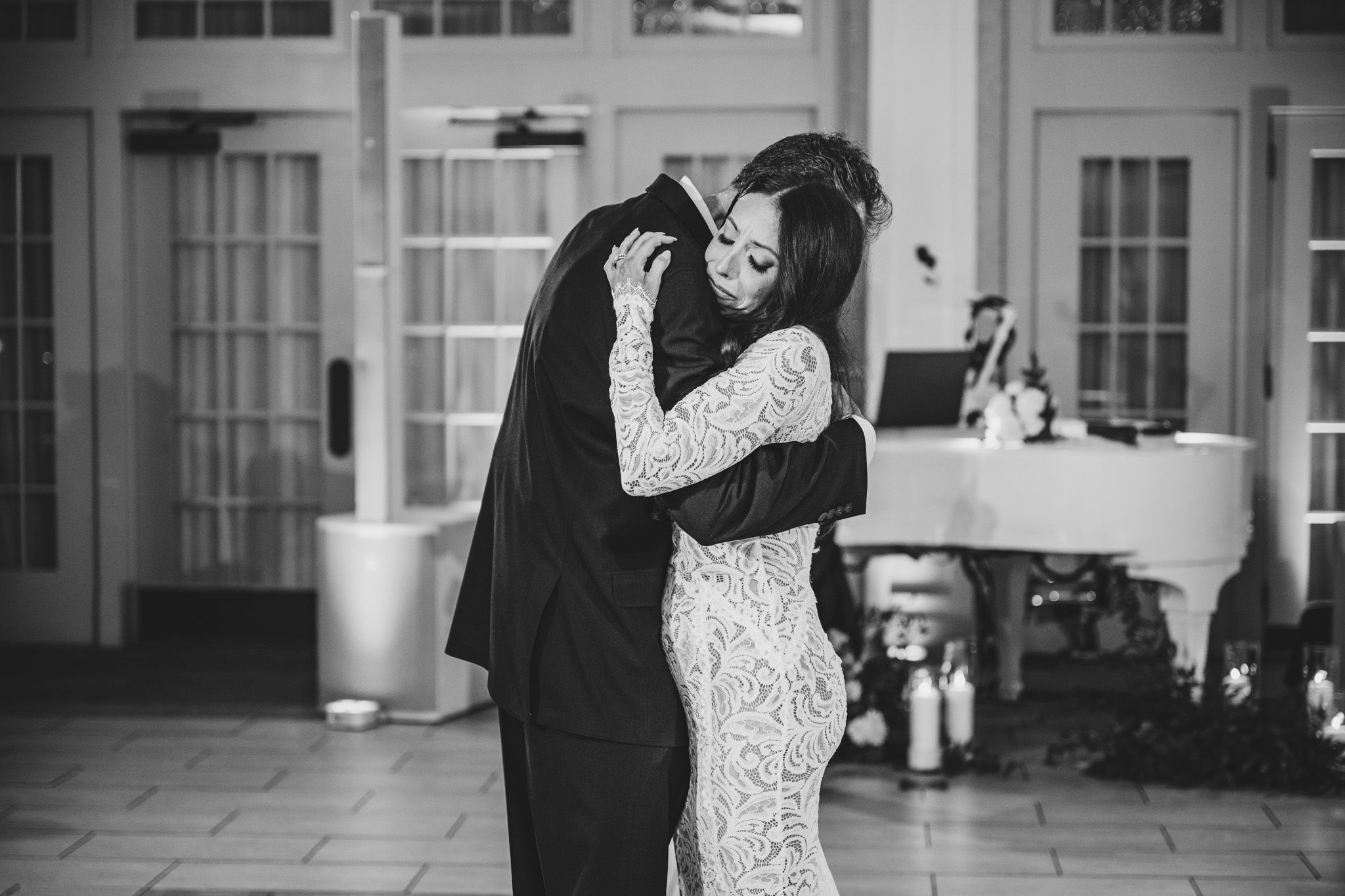 A tender moment captured in black and white during a wedding dance in an elegant ballroom.