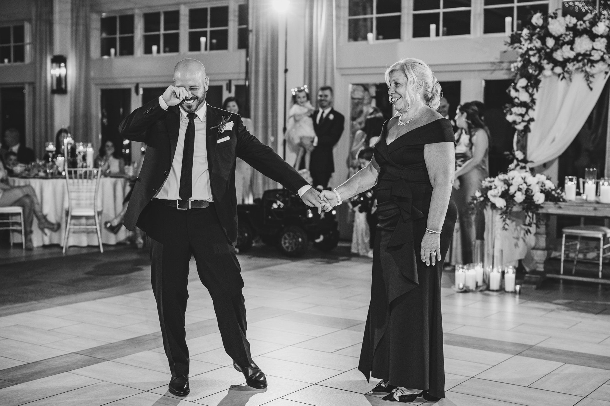 A black and white photo showing guests dancing energetically at a wedding reception.