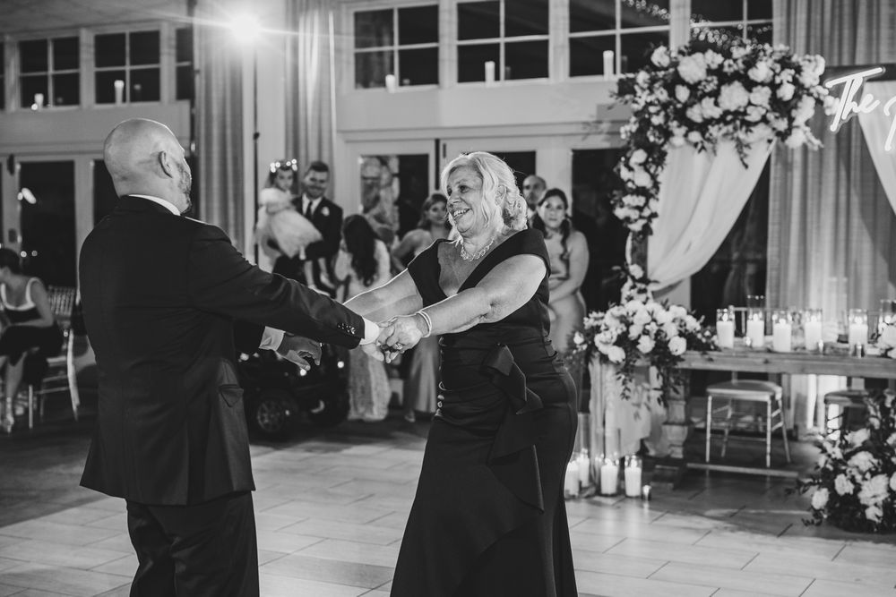 Black and white image of guests enjoying a dance together at an elegant wedding reception.