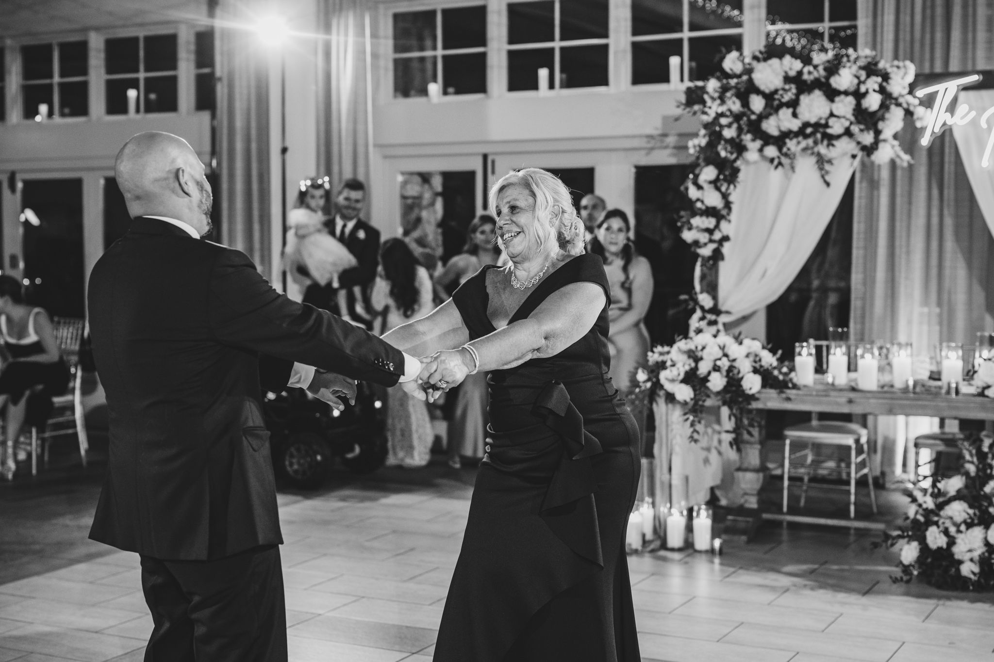 Black and white image of guests enjoying a dance together at an elegant wedding reception.