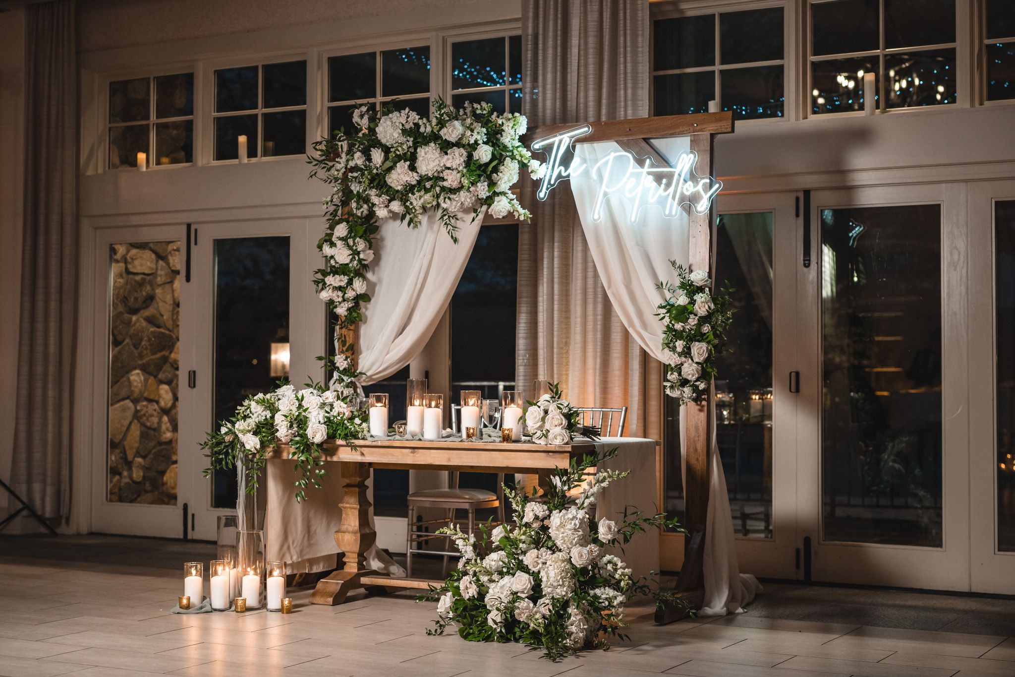 Wedding reception decor with floral arch, candles and rustic wooden table display.