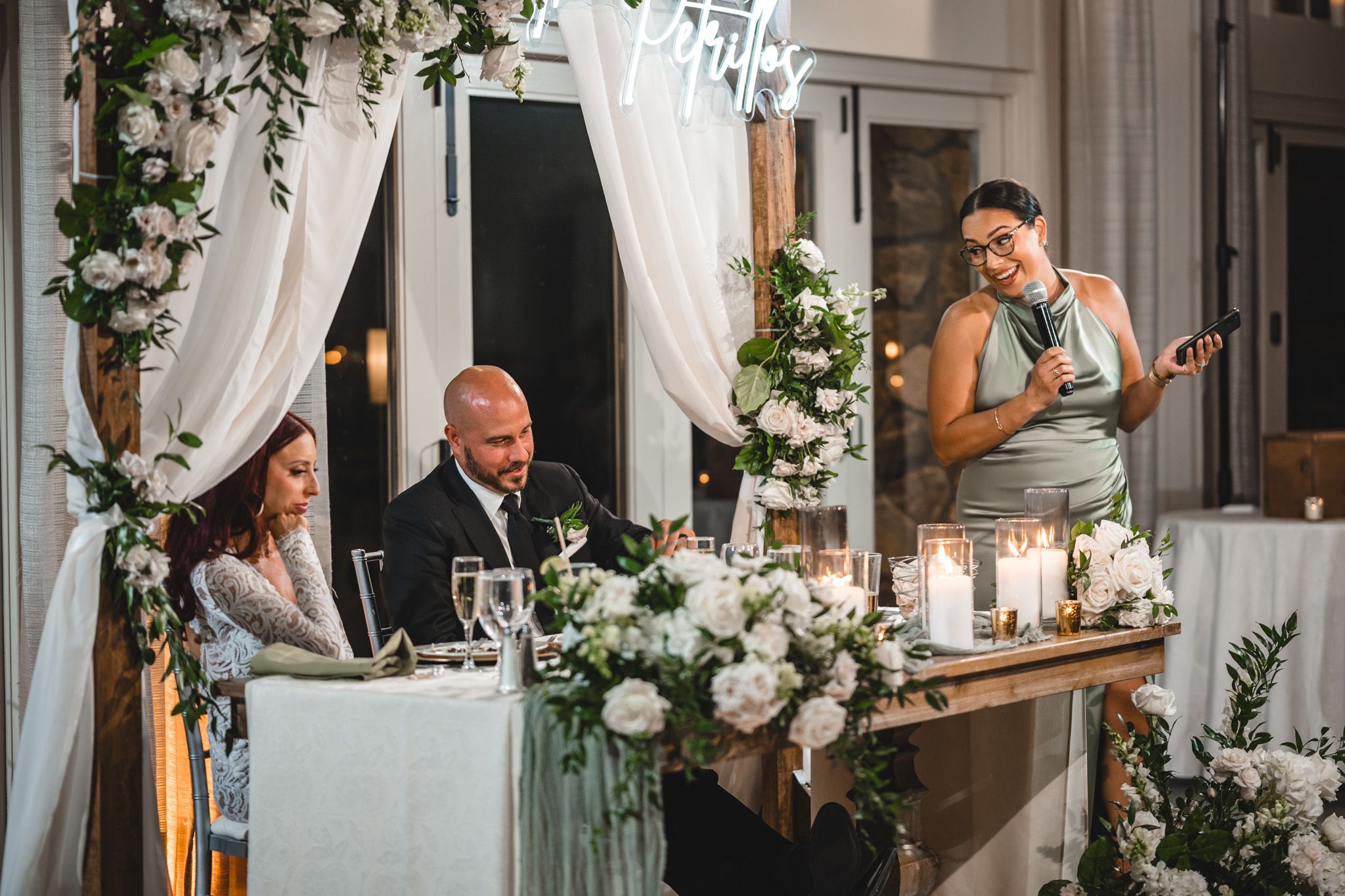 Candlelit wedding reception table decorated with white roses and elegant draping.