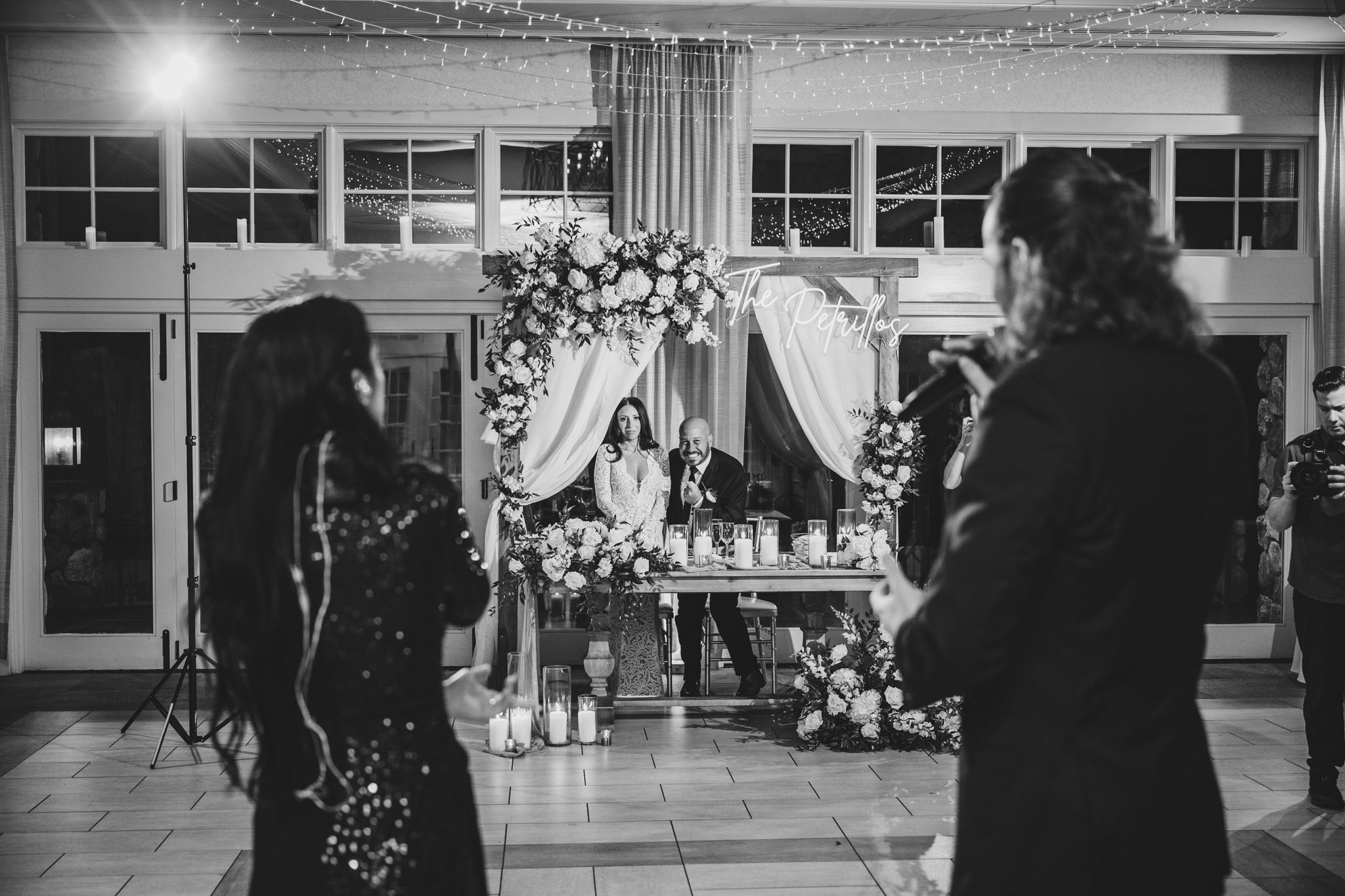 Wedding guests dance and celebrate on an elegant indoor dance floor under string lights.