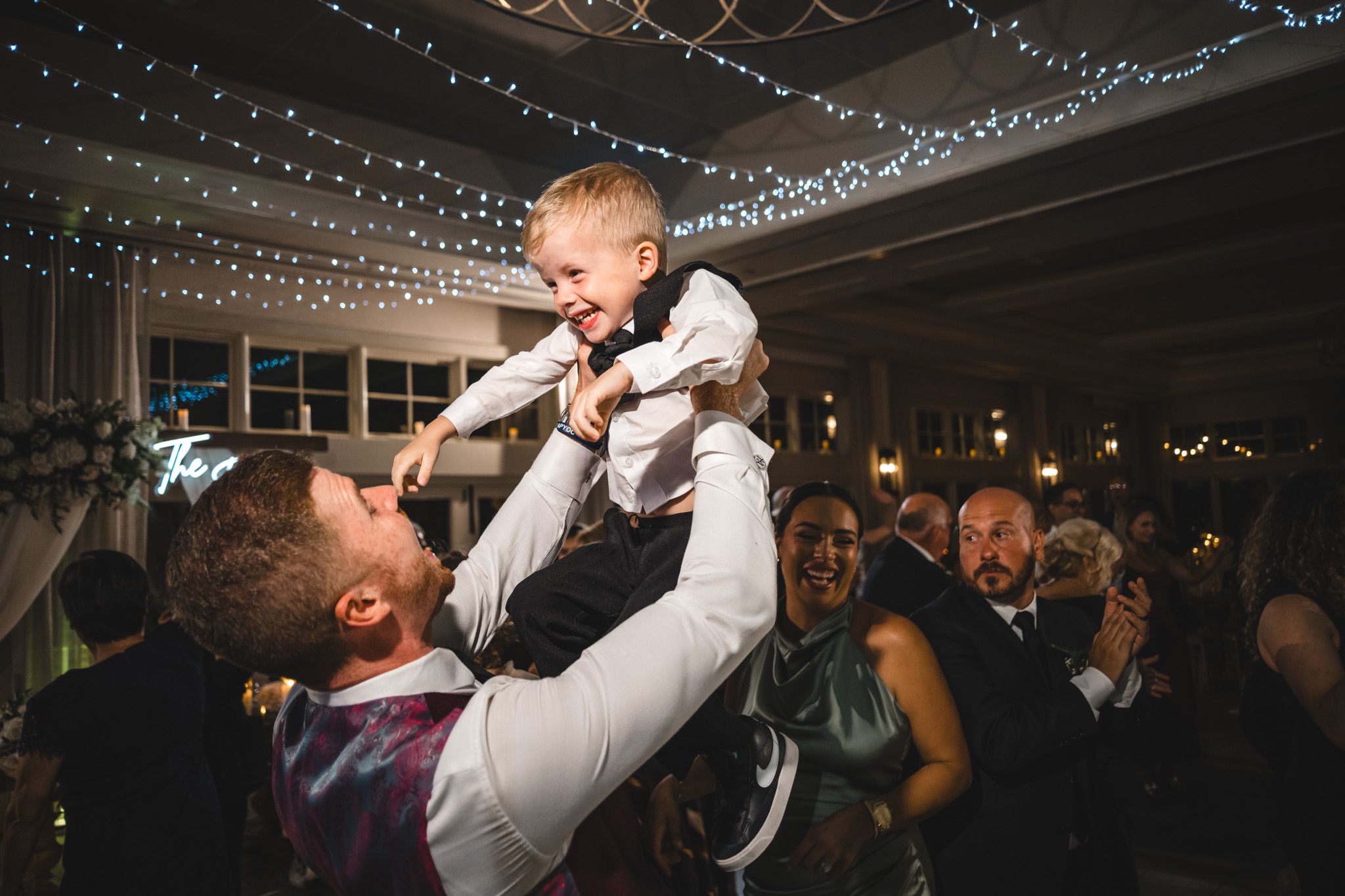Reception dance floor illuminated with twinkling string lights as guests celebrate.