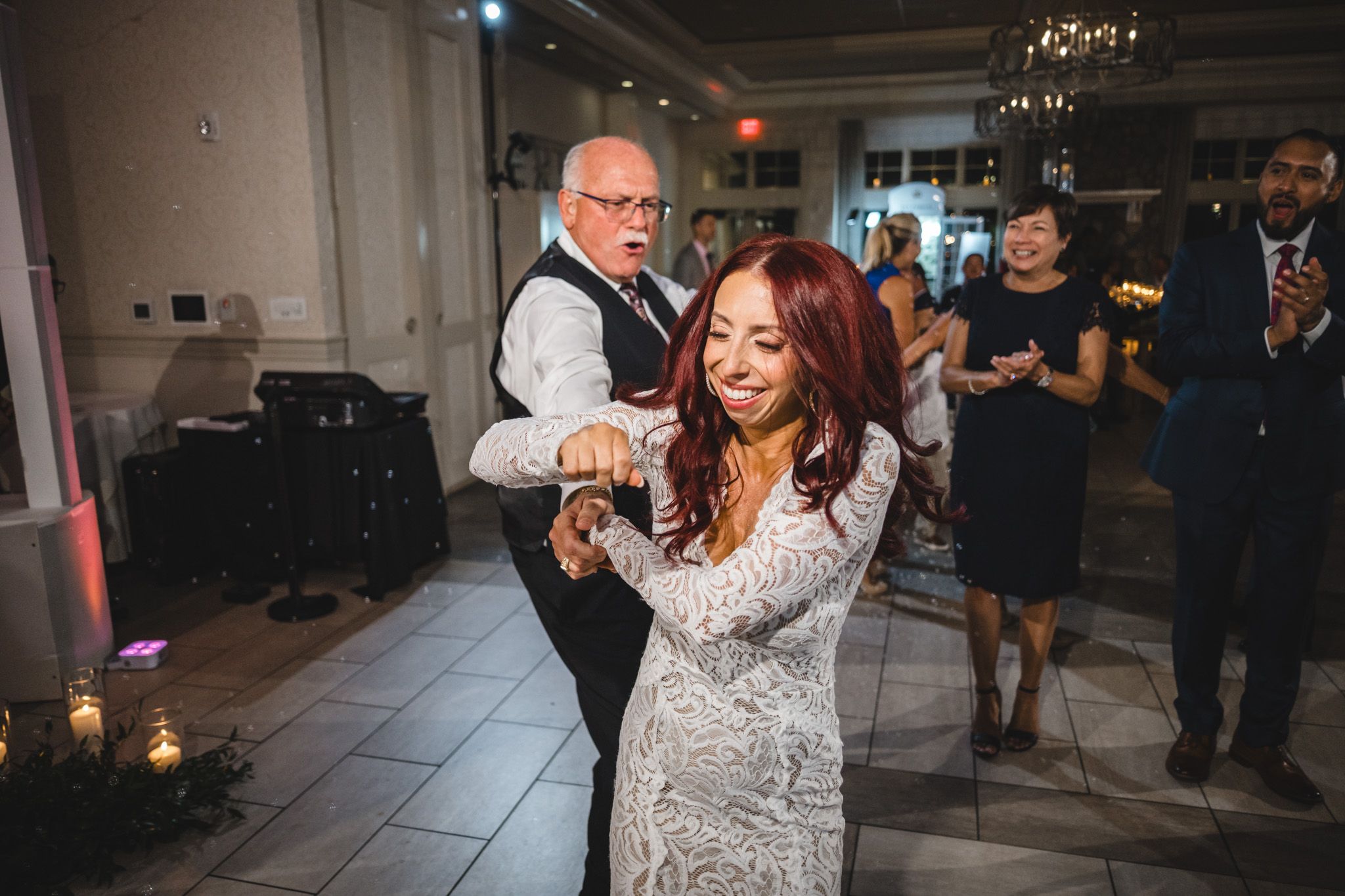 Lively dance party at wedding reception with guests in formal attire.