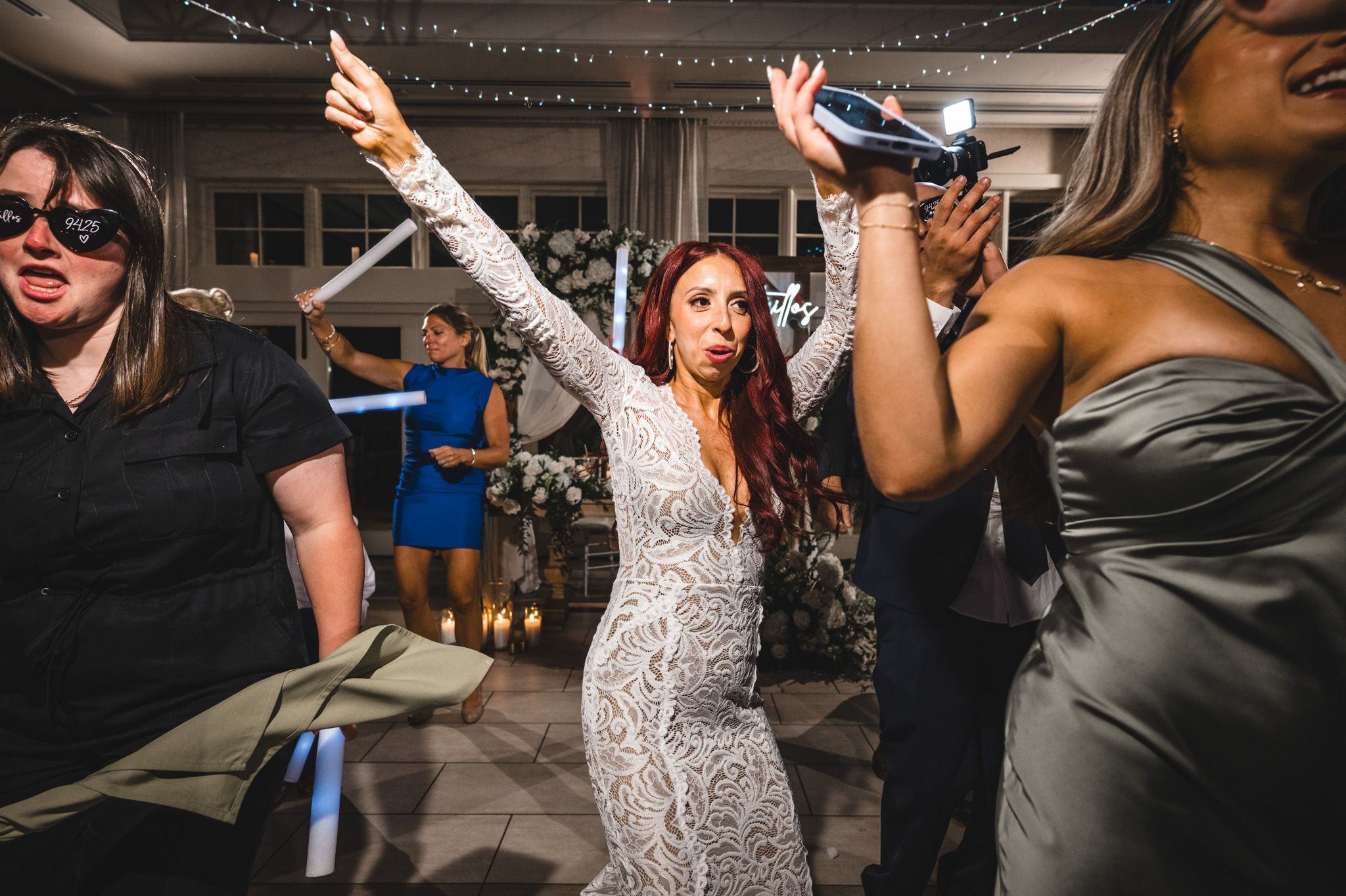 Celebratory dance party scene with guests wielding light sabers under decorative string lighting.