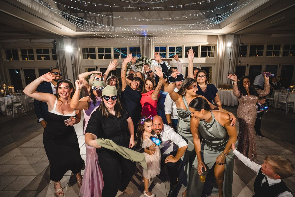Wedding guests dancing and celebrating on a dance floor under twinkling lights.