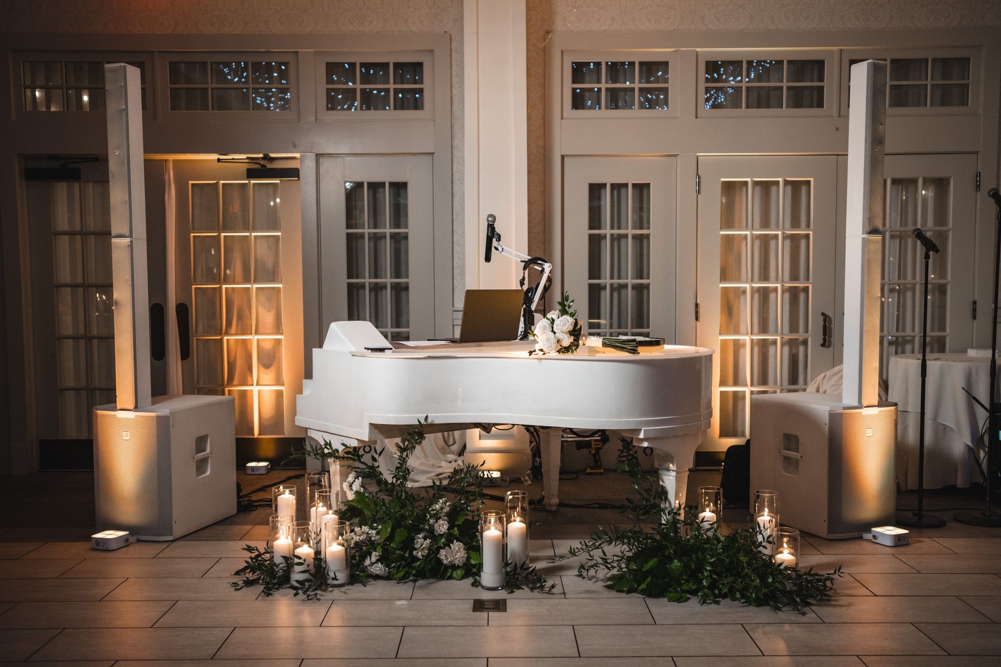 White grand piano decorated with candles and greenery for an elegant wedding ceremony setup.