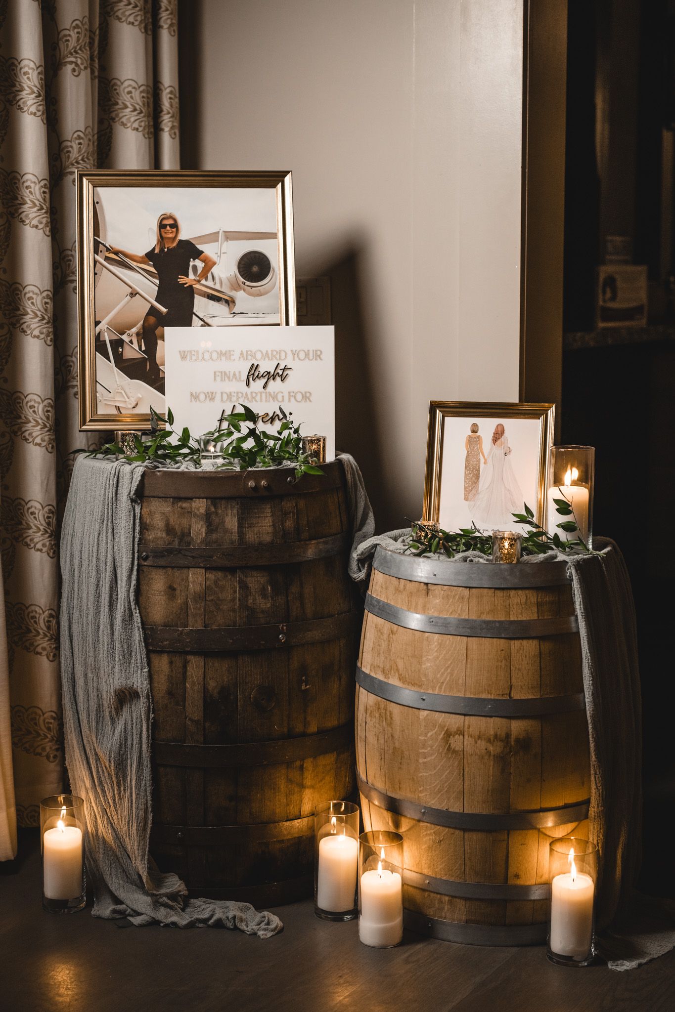 Rustic wedding decor display with wooden wine barrels, framed photos and glowing candles.
