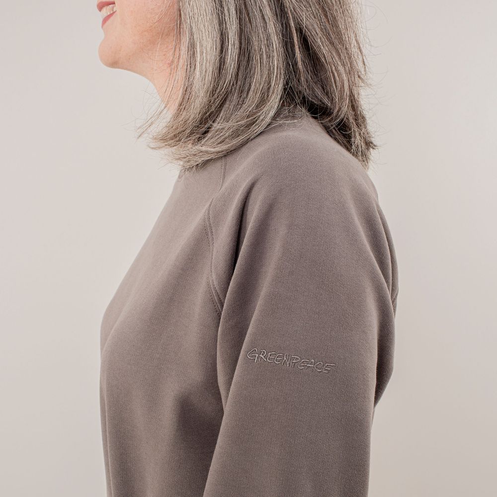 Person in gray turtleneck sweater shown from side profile against neutral background.