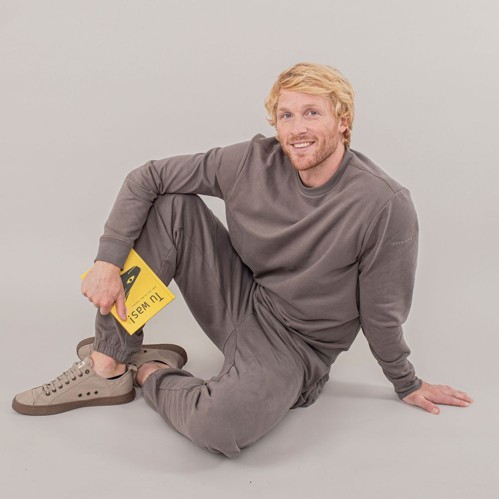 Person in gray loungewear demonstrates relaxed poses on light gray background showing comfortable casual wear.