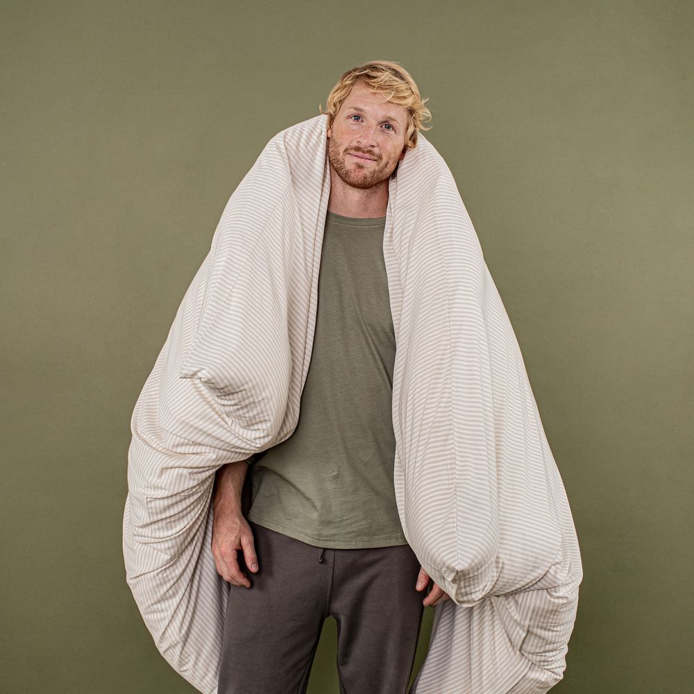 Person wearing white cardigan and gray outfit poses against olive green background showing casual style.