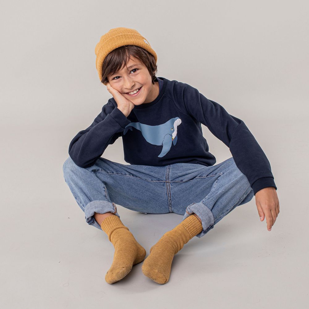Person in navy sweater and jeans sitting and reclining in various casual poses on light gray background.