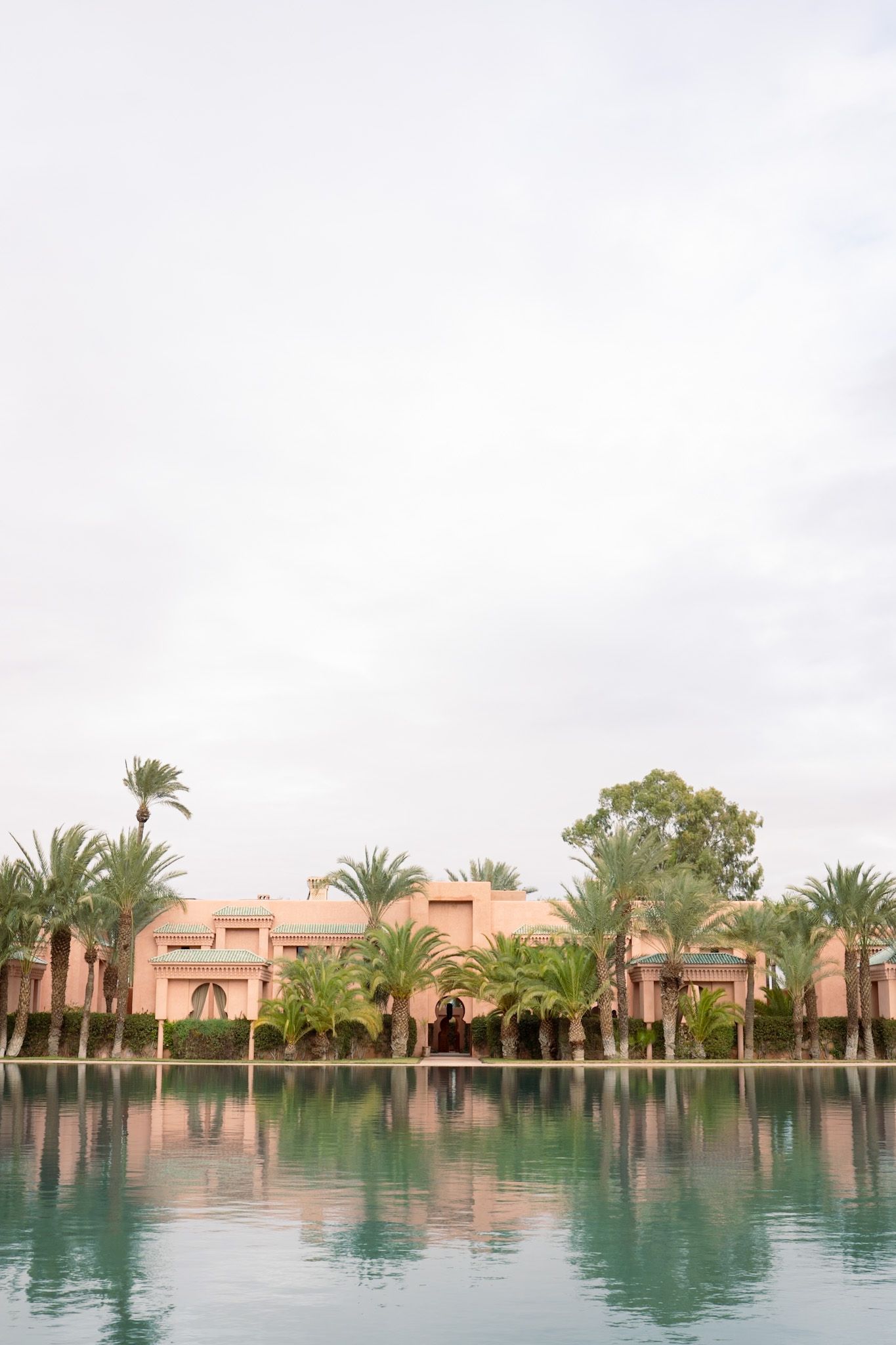 Arched courtyard views of a Mediterranean-style resort with palm trees and manicured gardens through multiple frames.