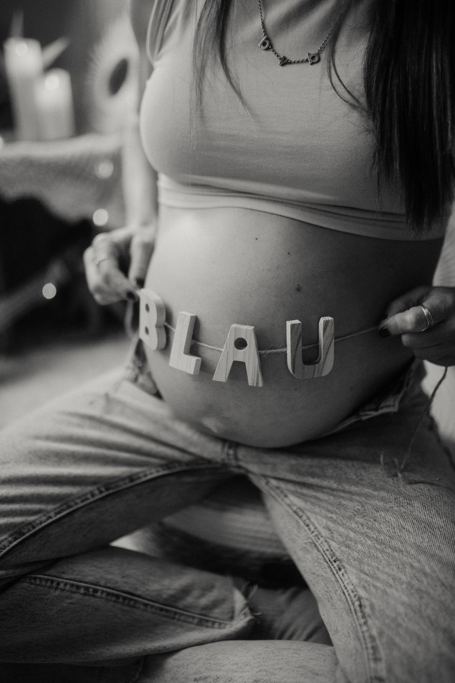 Barriga embarazada con el nombre del bebé en letras de madera en sesión en blanco y negro